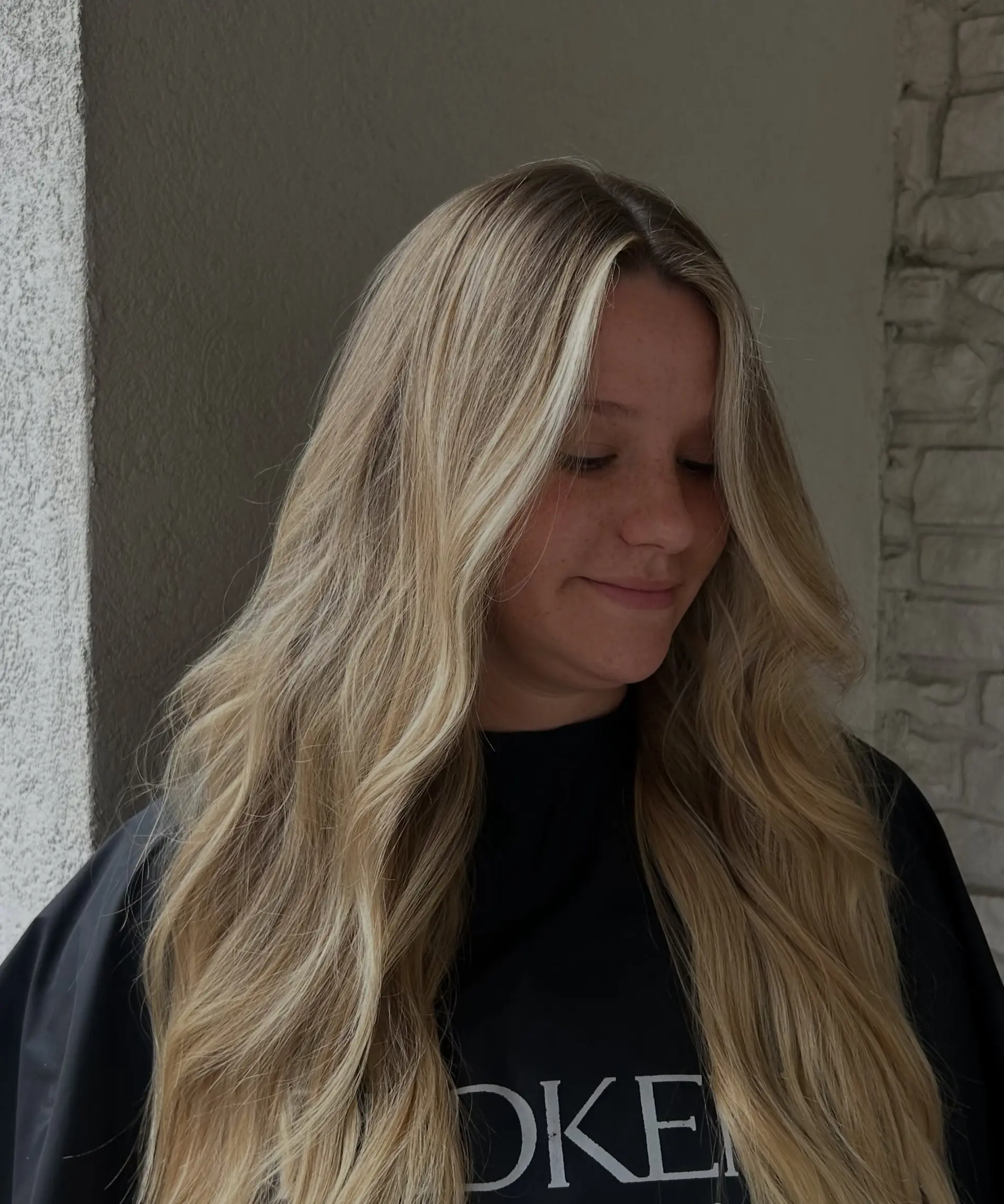 Long dimensional blonde hair with face-framing bright pieces styled in soft flowing waves. 1