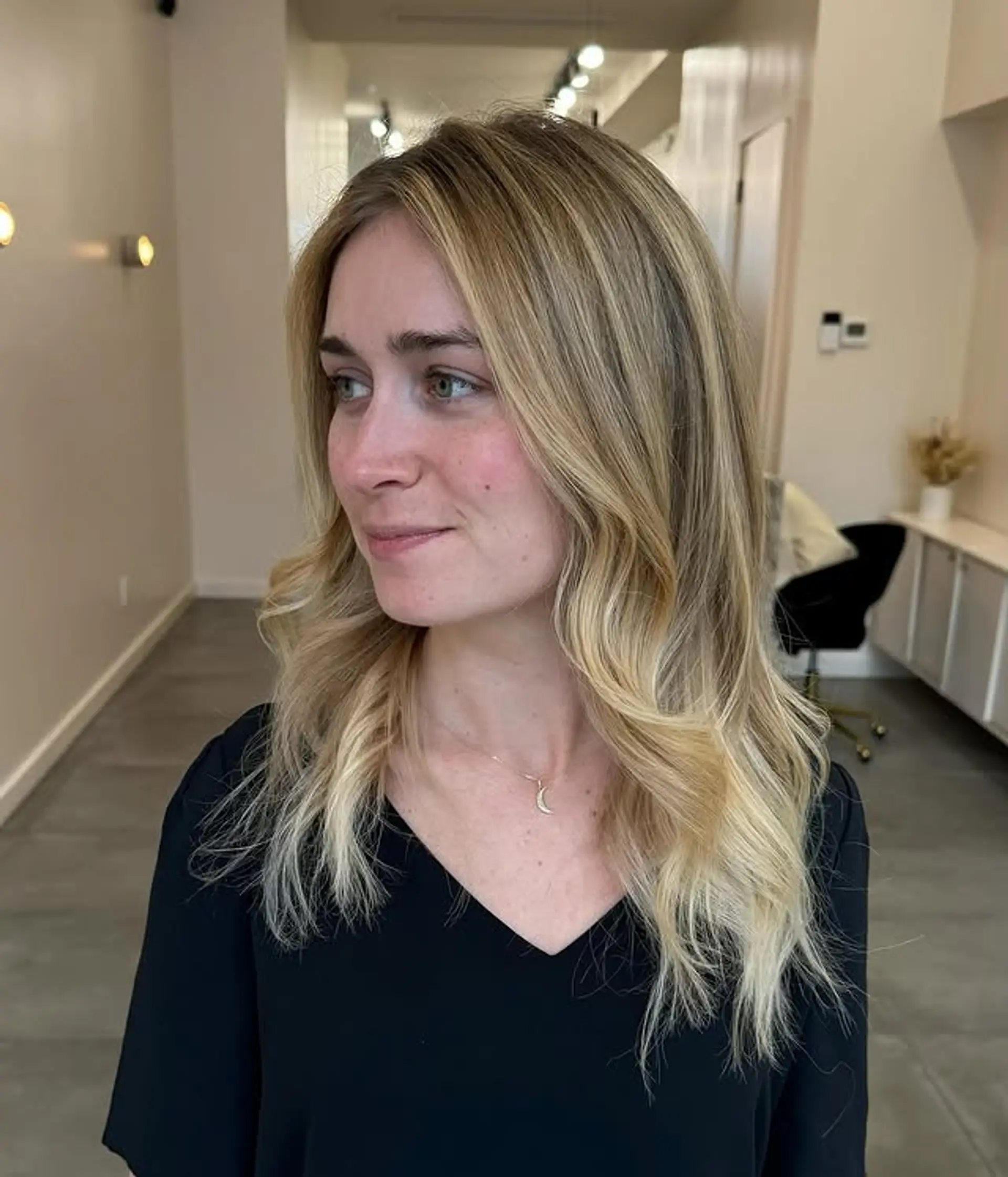 A medium-length wavy hairstyle with a beachy blonde balayage and soft layers. 1