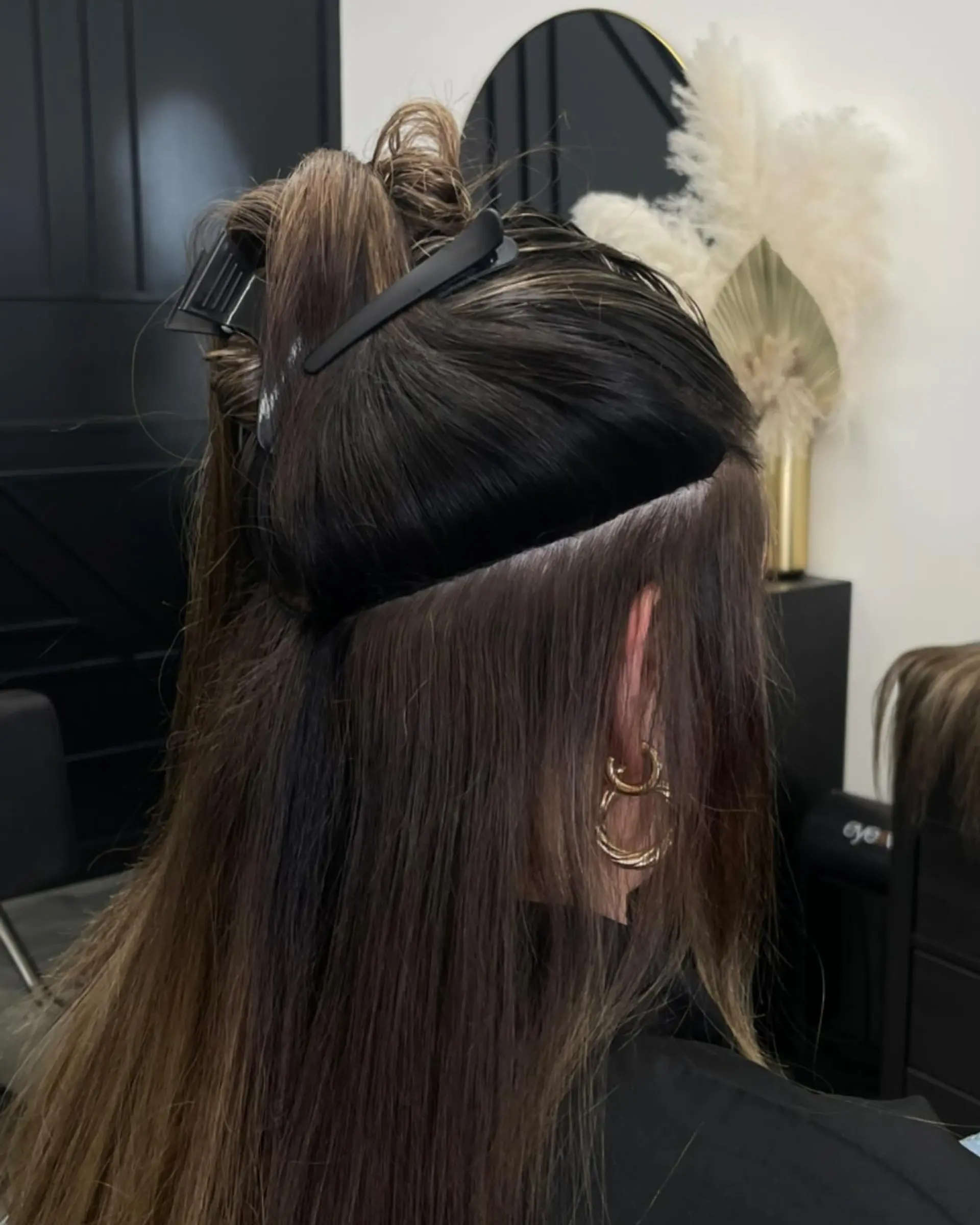 Straight brunette hair clipped up to demonstrate seamless hand-tied extension application. 1