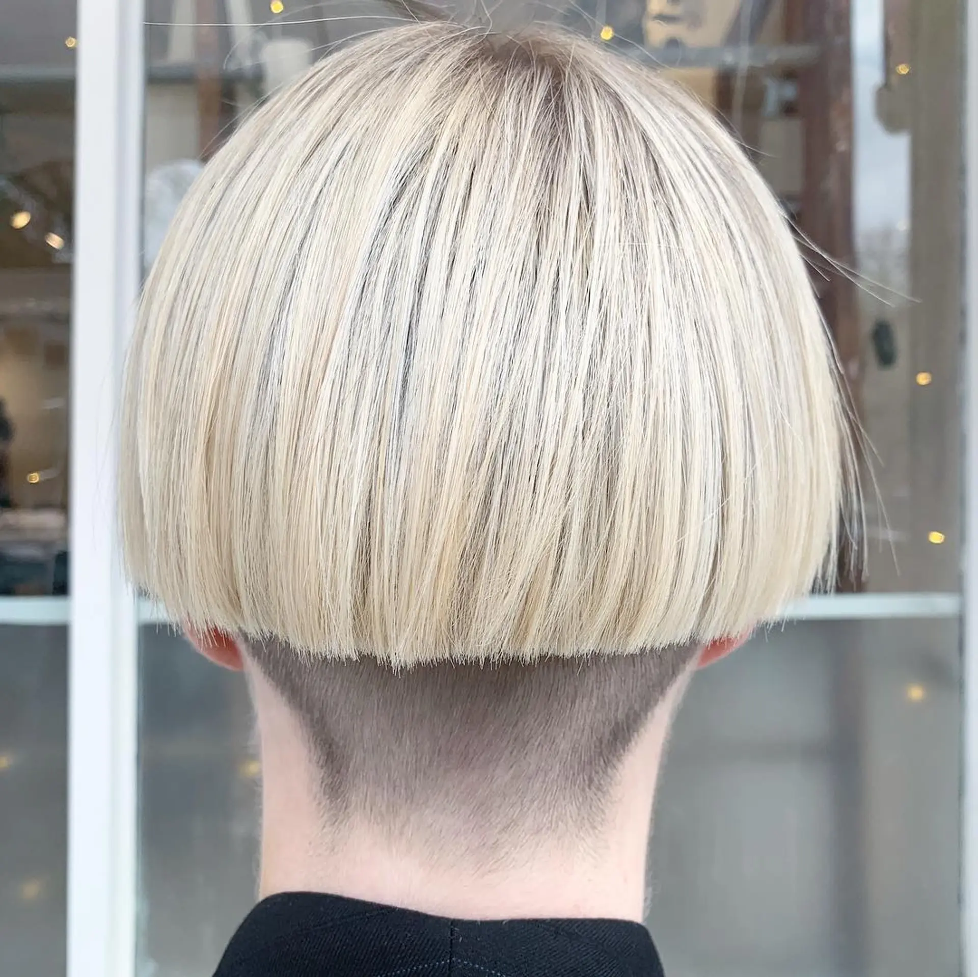 A sleek, blonde bowl cut with a straight texture, short length, and a sharp undercut at the nape for a modern, uniform appearance. 1