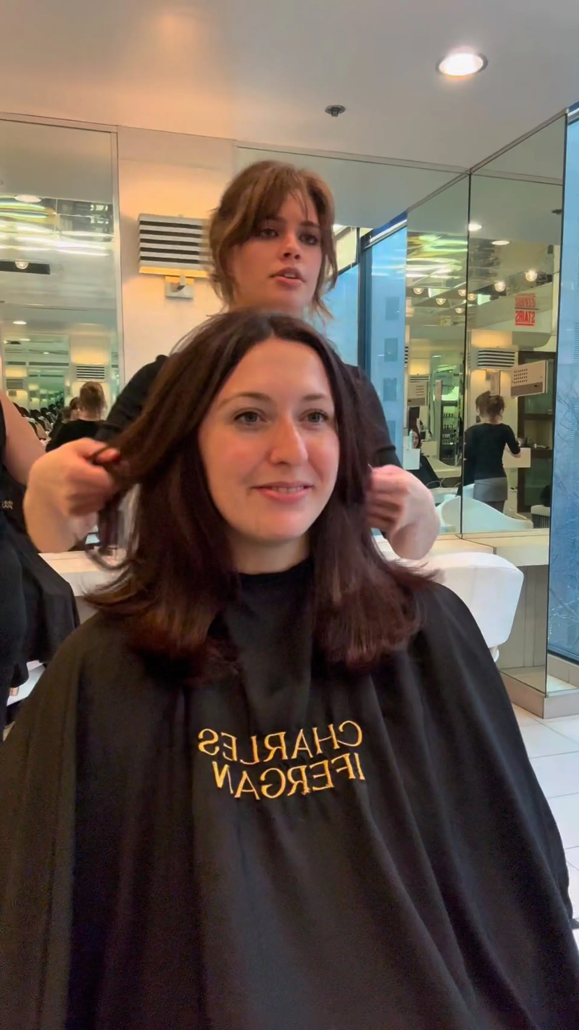 Medium-length dark brunette hair cut with soft framing layers and styled into a smooth, voluminous blowout. 1