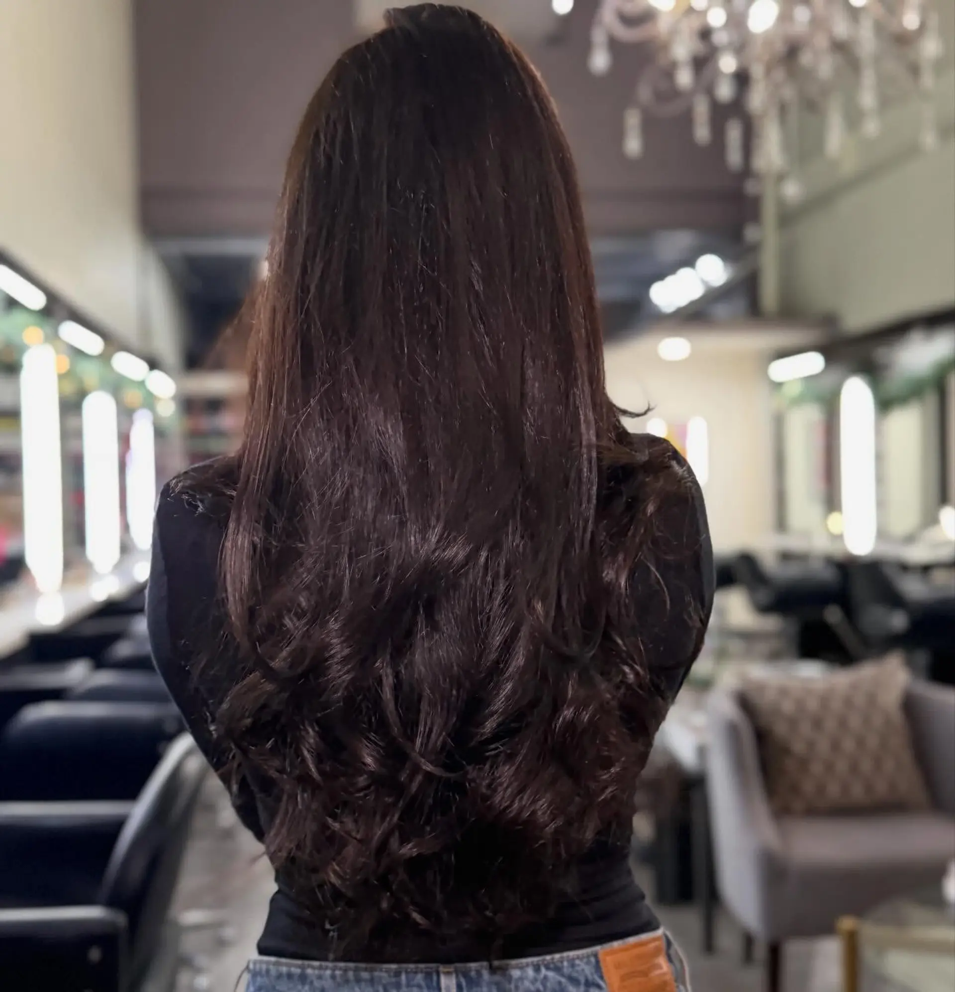 Long, rich dark brunette hair cut with soft cascading layers and styled with voluminous curls at the ends. 1