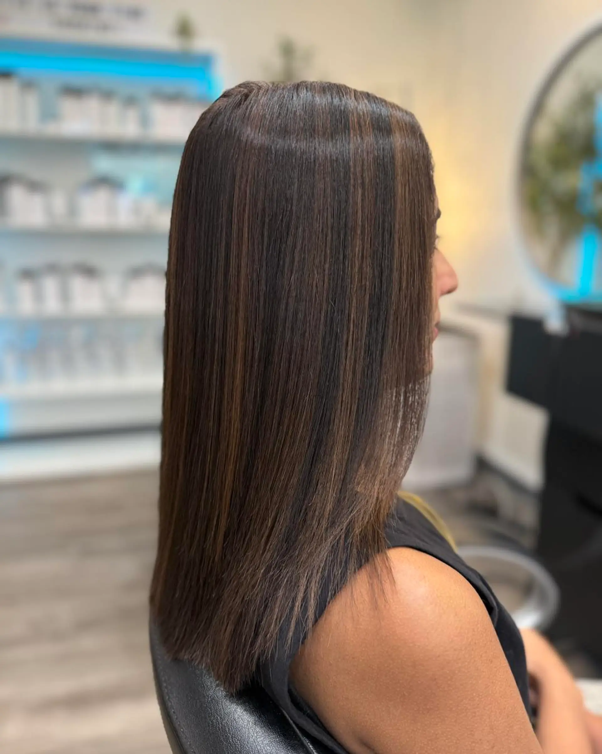 Straight, medium-length dark brown hair styled sleek with subtle, warm dimensional highlights throughout. 1