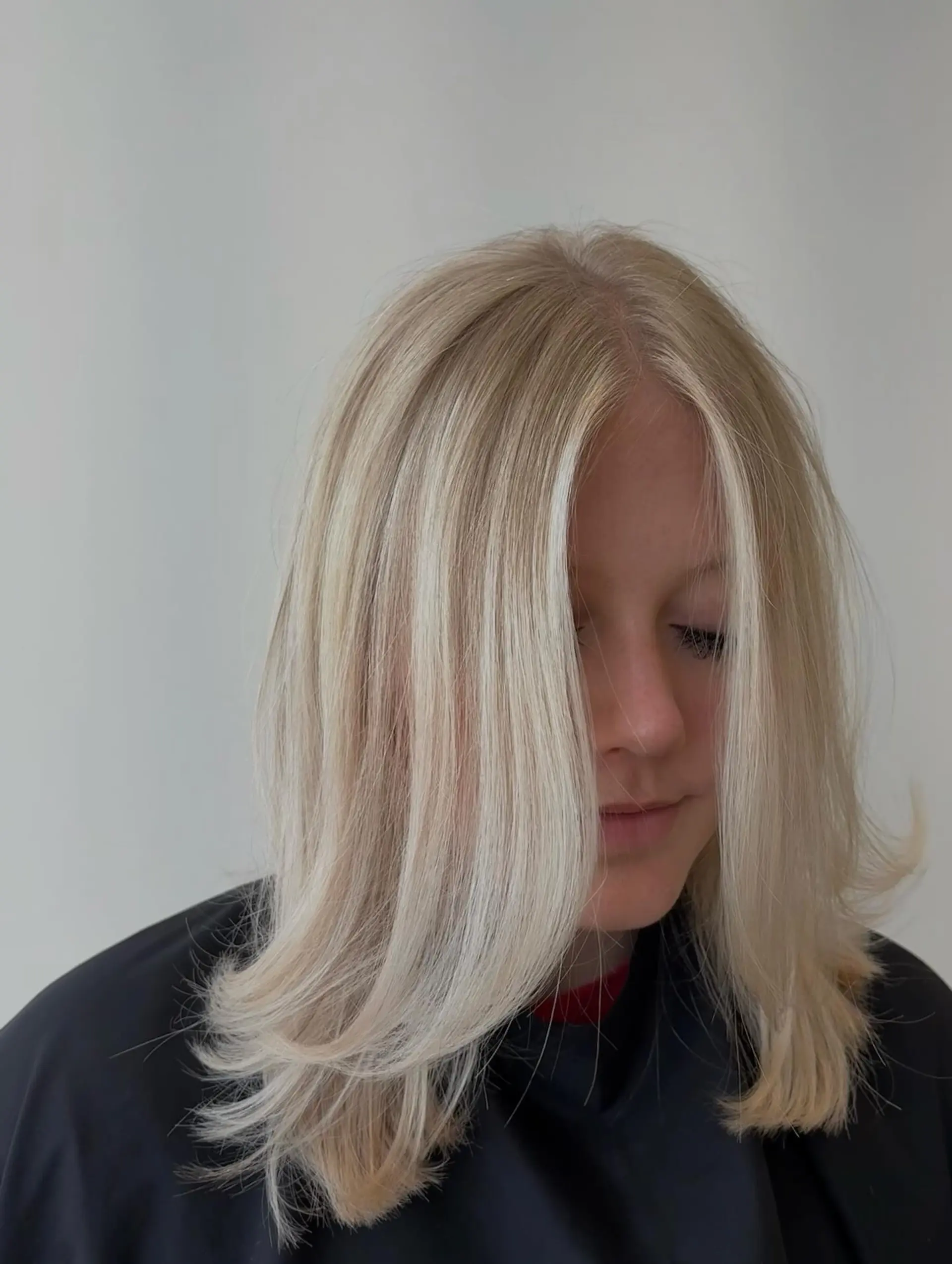 Medium-length bright blonde hair cut in soft layers with face-framing strands and outward-flipped ends. 1