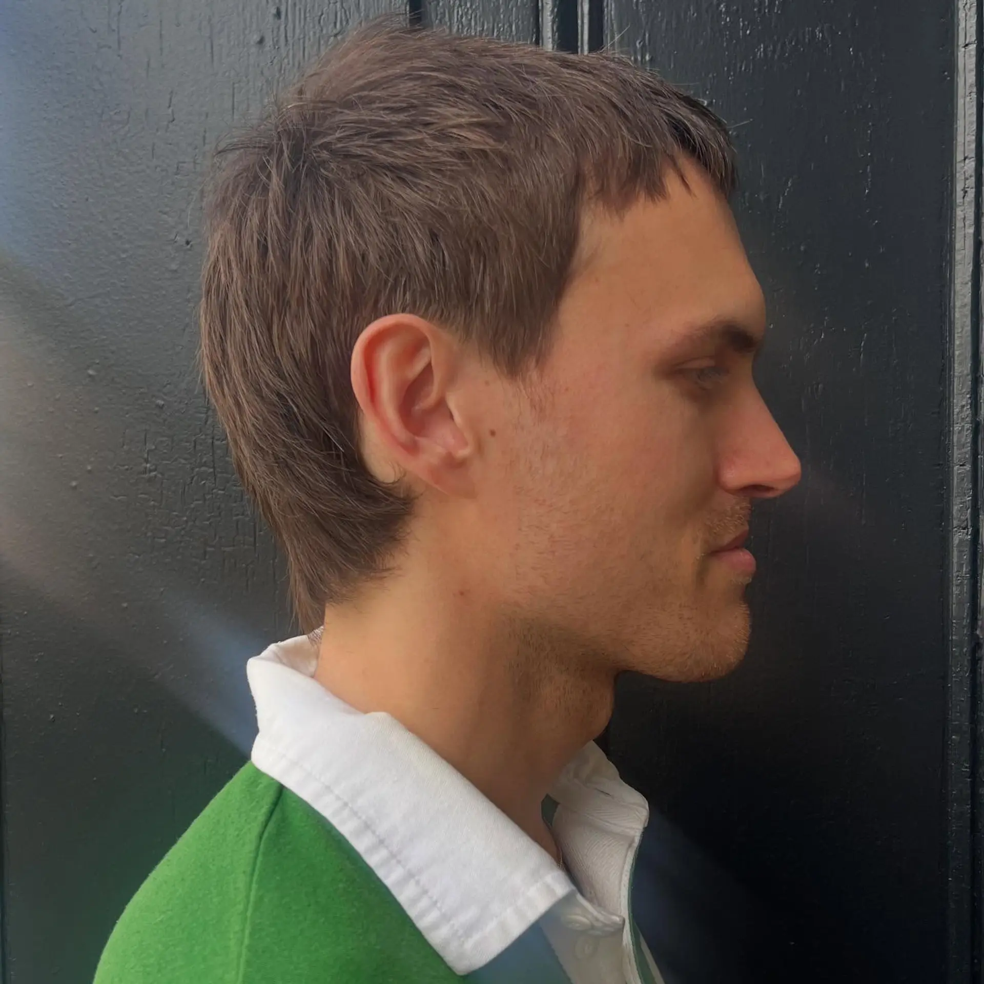 A side profile of a textured mod haircut with a short cropped fringe and soft tapering around the ears and nape. 1