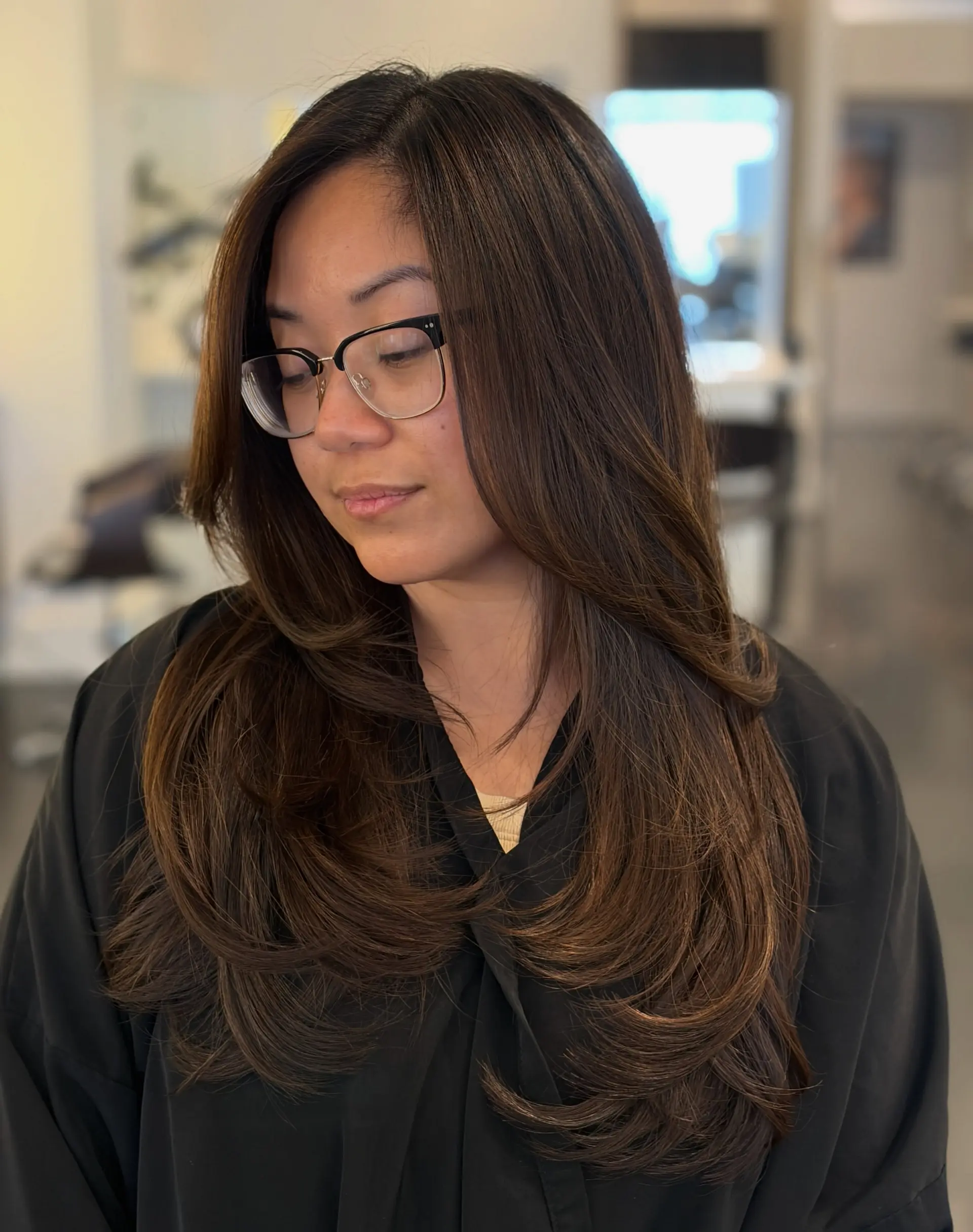 Long dark brown hair styled in a polished, layered blowout with rounded face-framing ends. 1