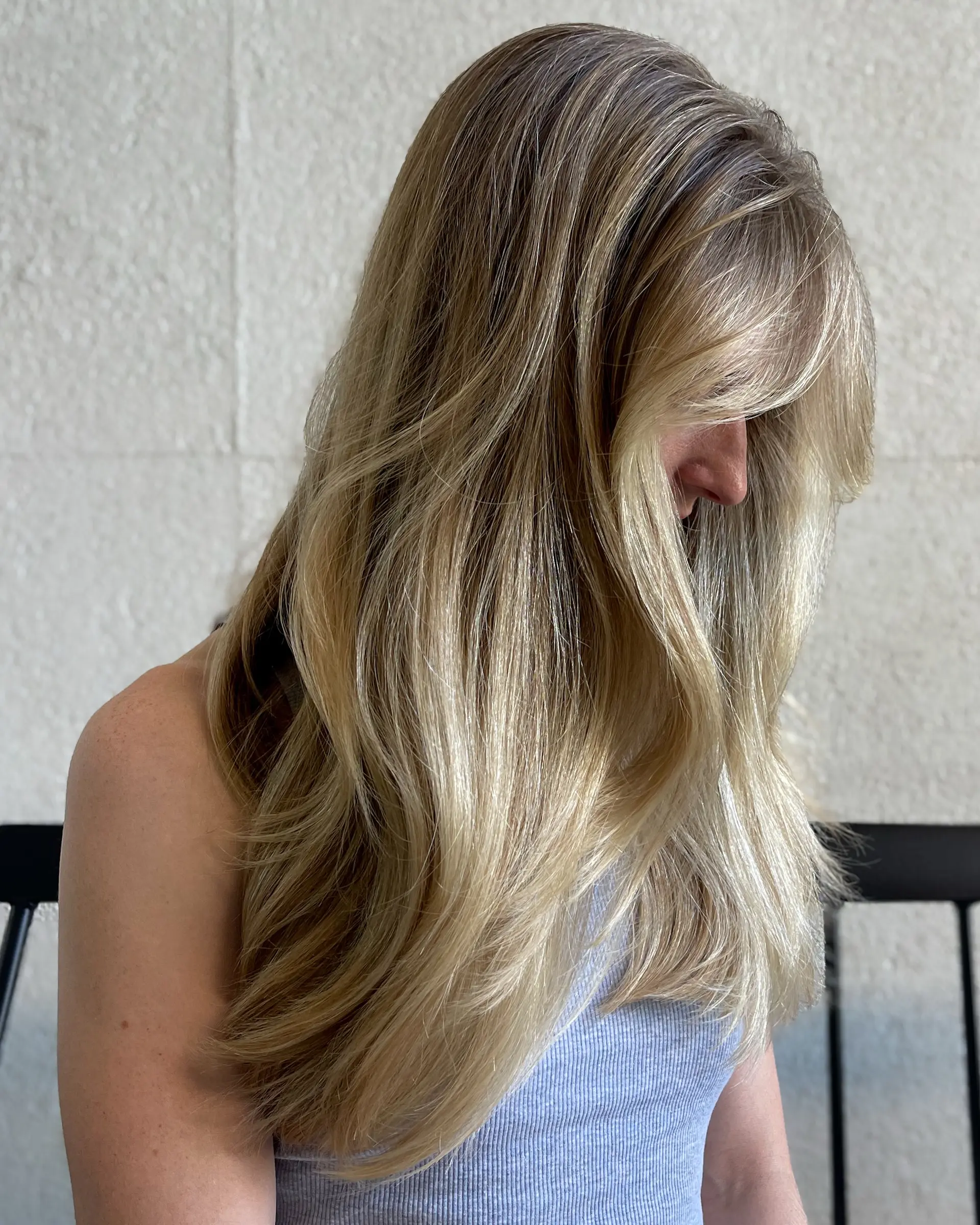 Long dimensional blonde hair styled in a smooth, polished blowout with soft layered movement and side-swept face framing. 1
