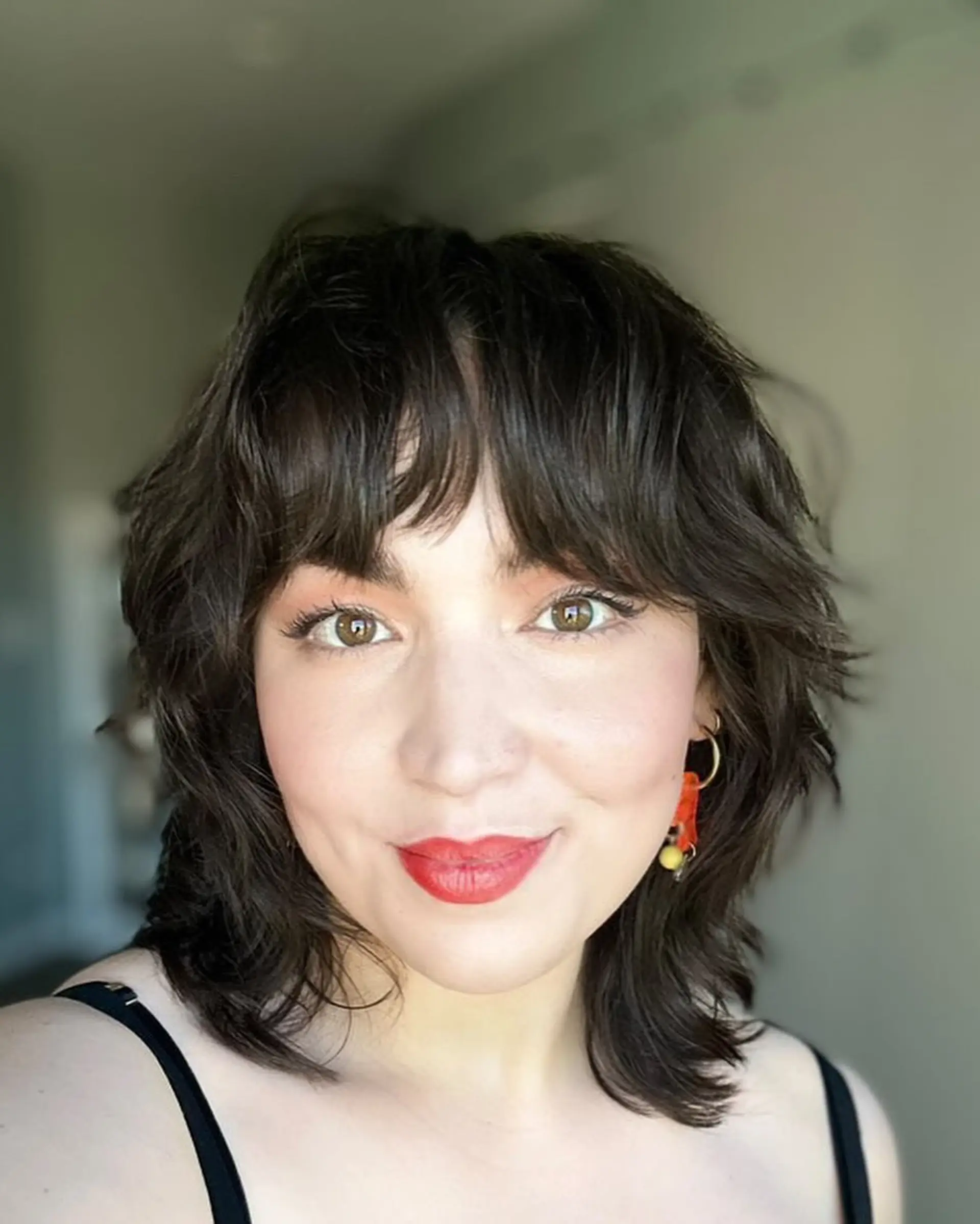 A medium-length shag haircut with textured layers and bangs. 1