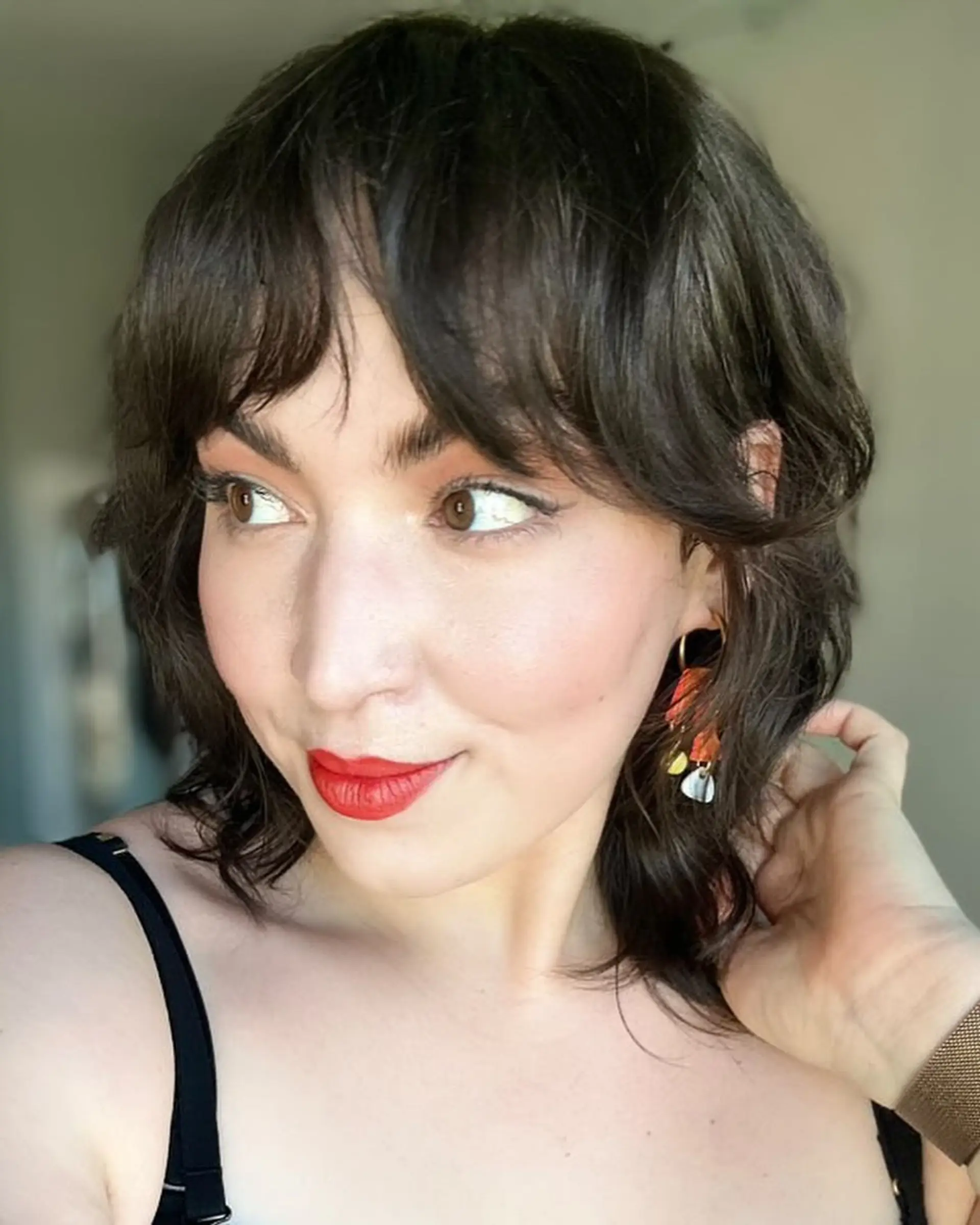 A medium-length shag haircut with textured layers and bangs. 2