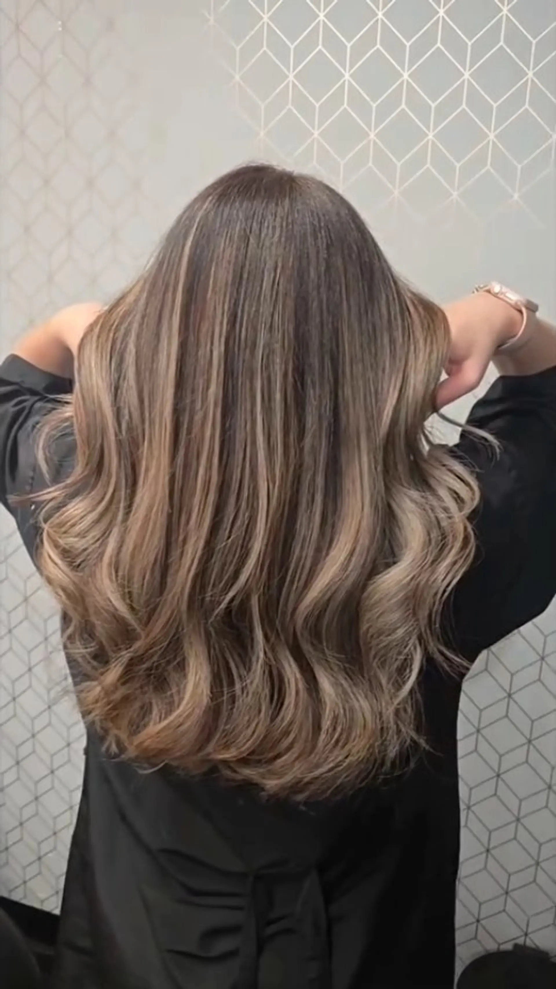 A cool-toned bronde balayage on long hair styled into smooth, cascading waves. 1