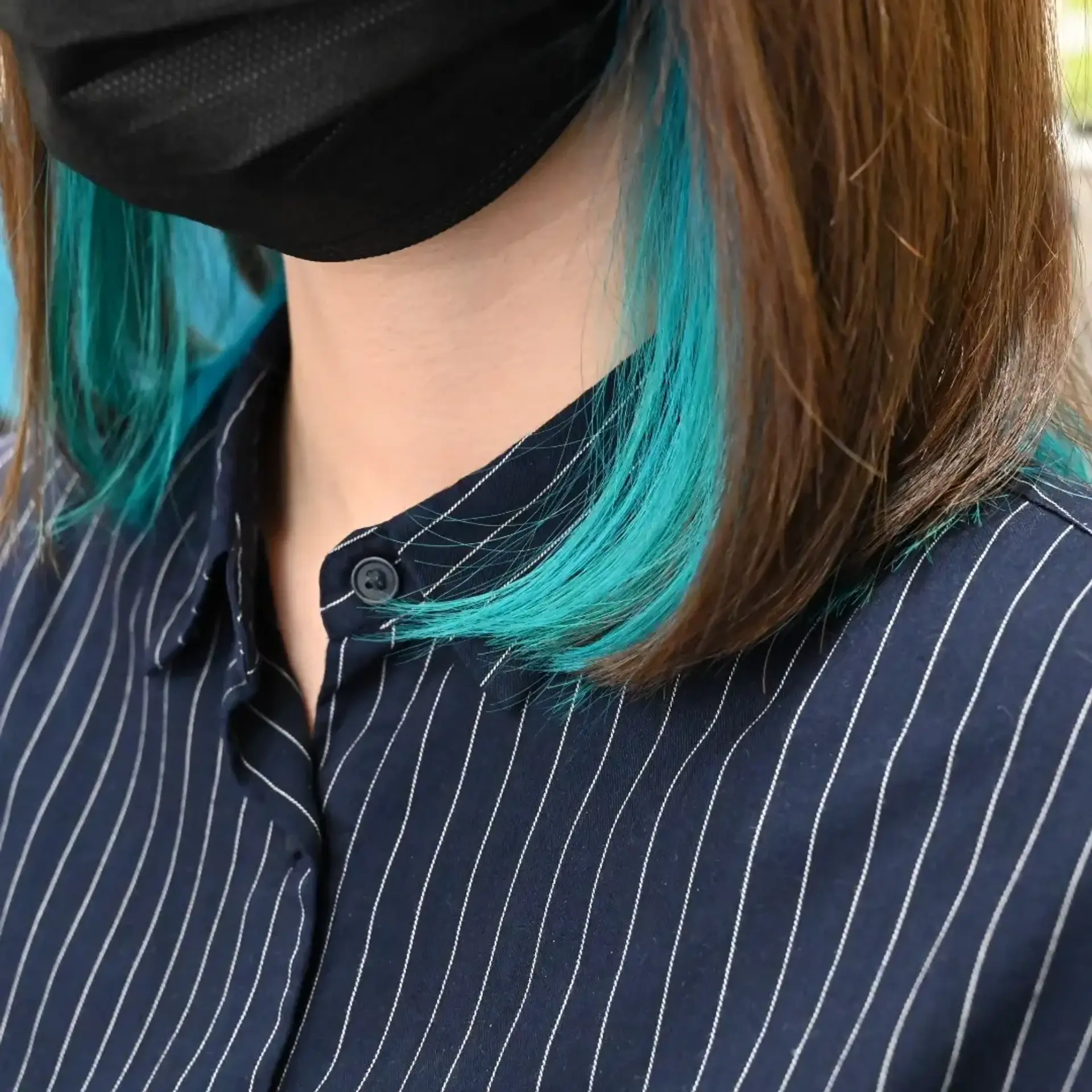 A sleek shoulder-length brown bob featuring vibrant turquoise teal peekaboo highlights placed underneath. 1