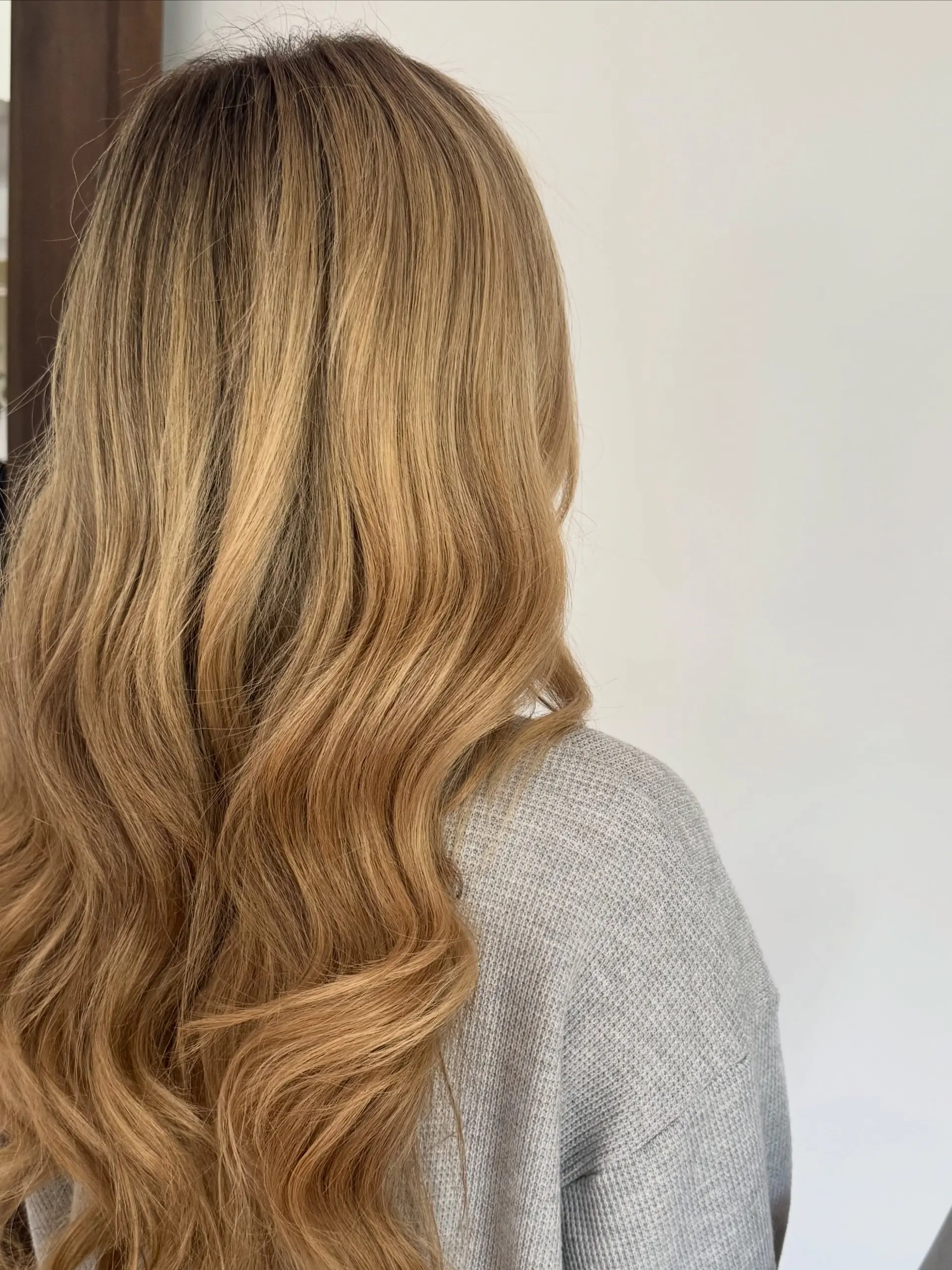 Long honey blonde hair styled with soft, cascading loose waves viewed from behind. 1