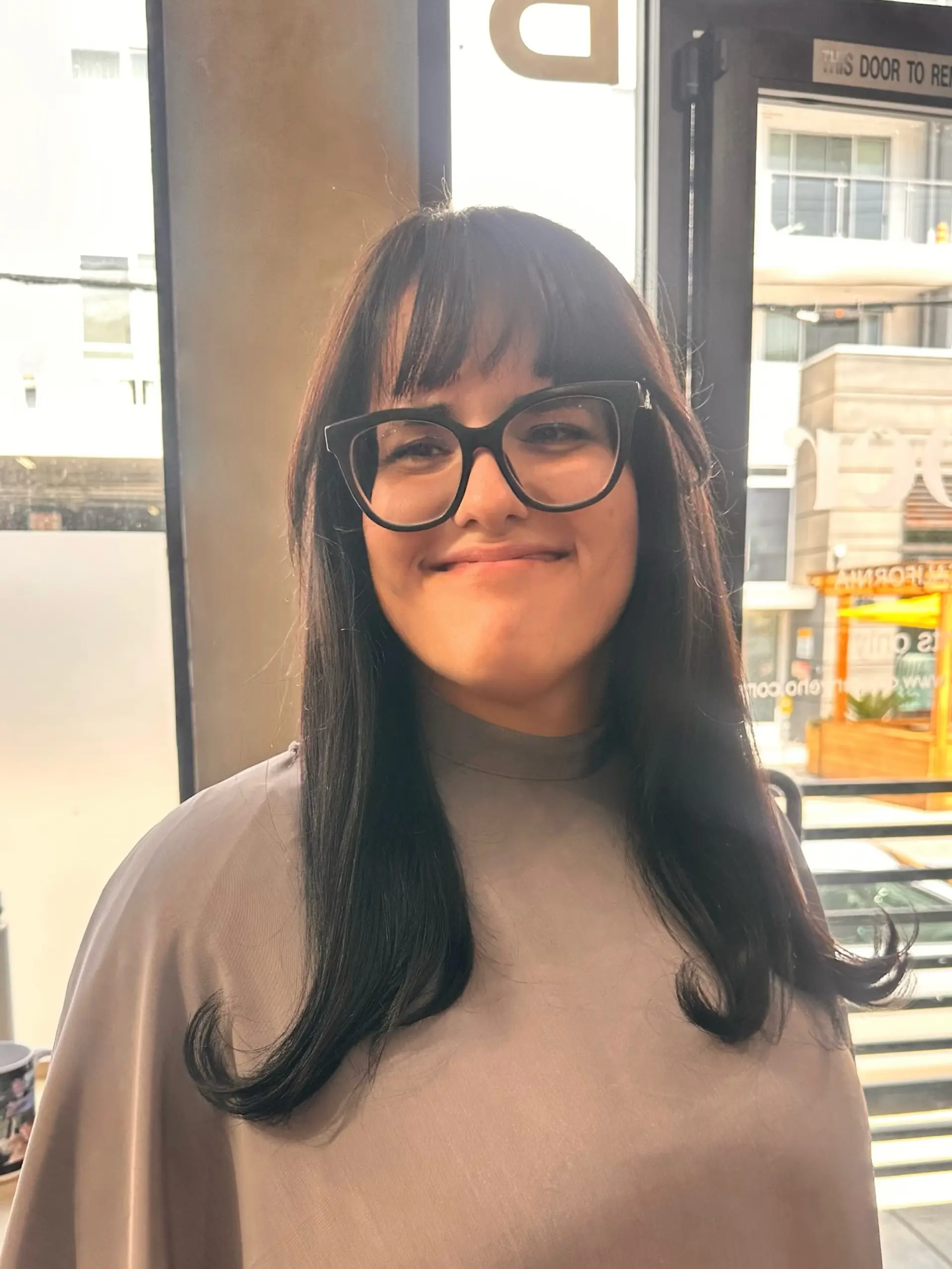 A sleek dark brunette hairstyle featuring straight eyebrow-skimming bangs and long lengths styled with outward flipped ends. 1