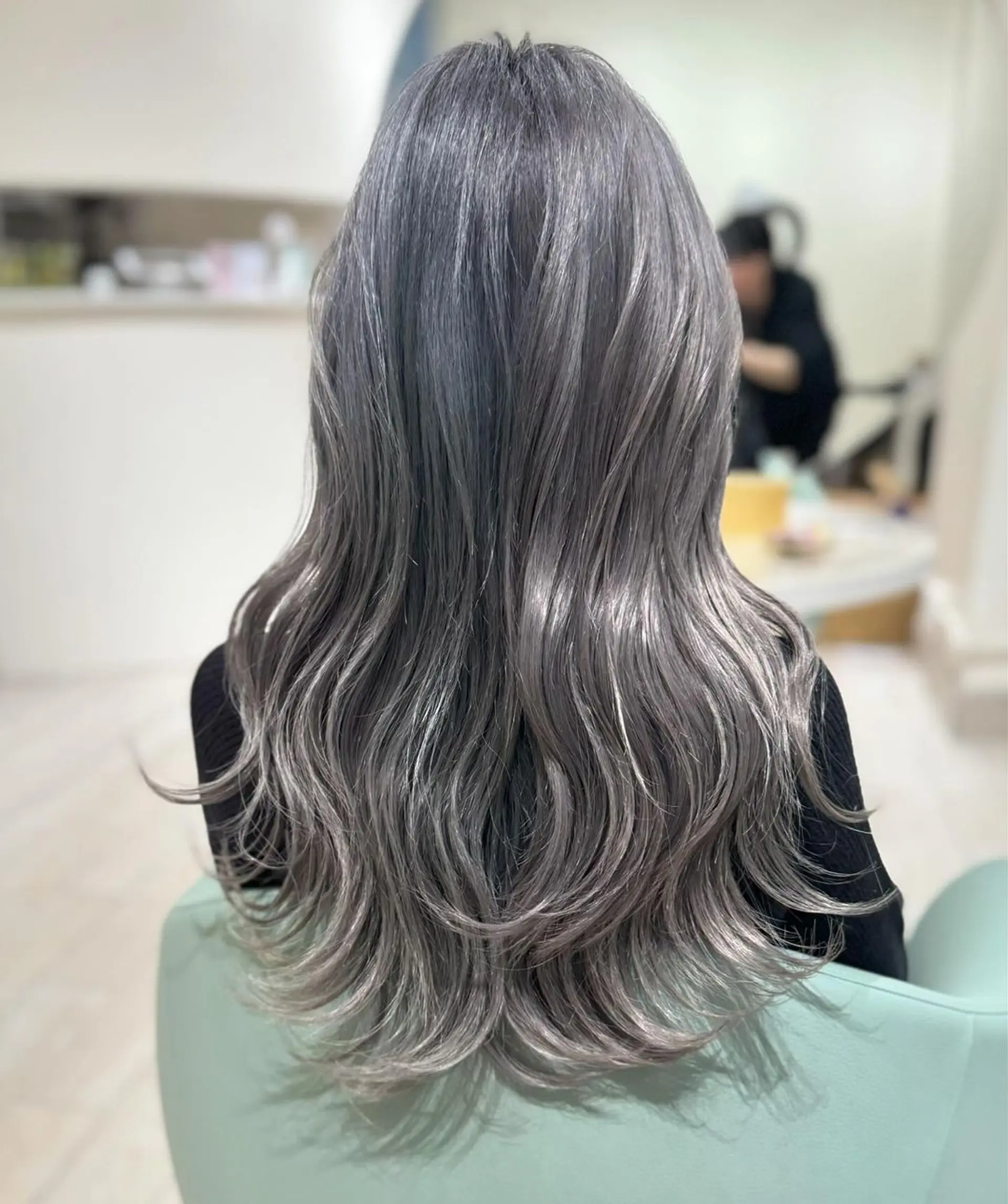 Long, wavy hair dyed in dimensional silver and grey with ash undertones, featuring soft waves and layered ends. 1
