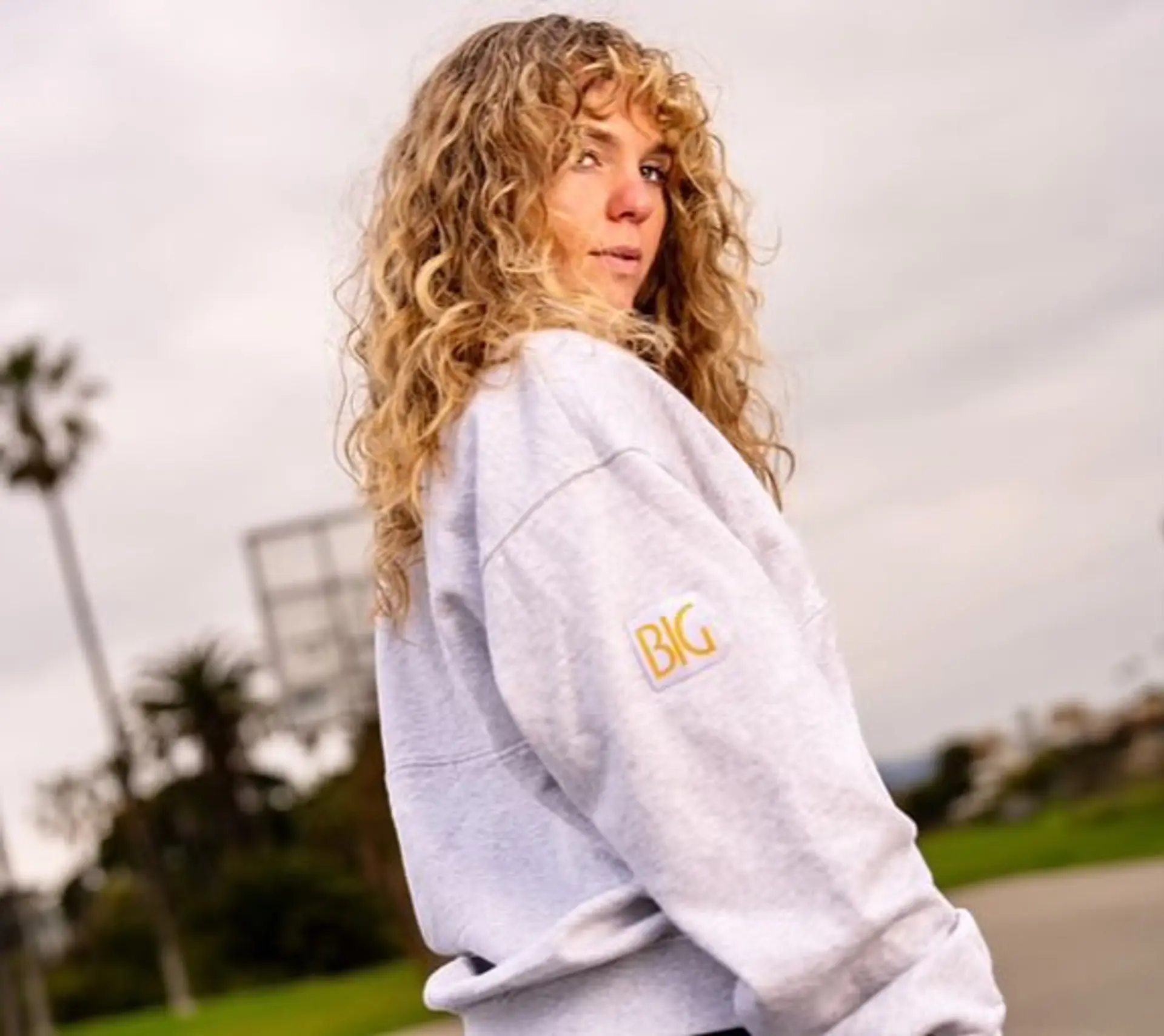 Medium-length curly shag featuring defined ringlets, full curly bangs, and dimensional golden blonde highlights. 1