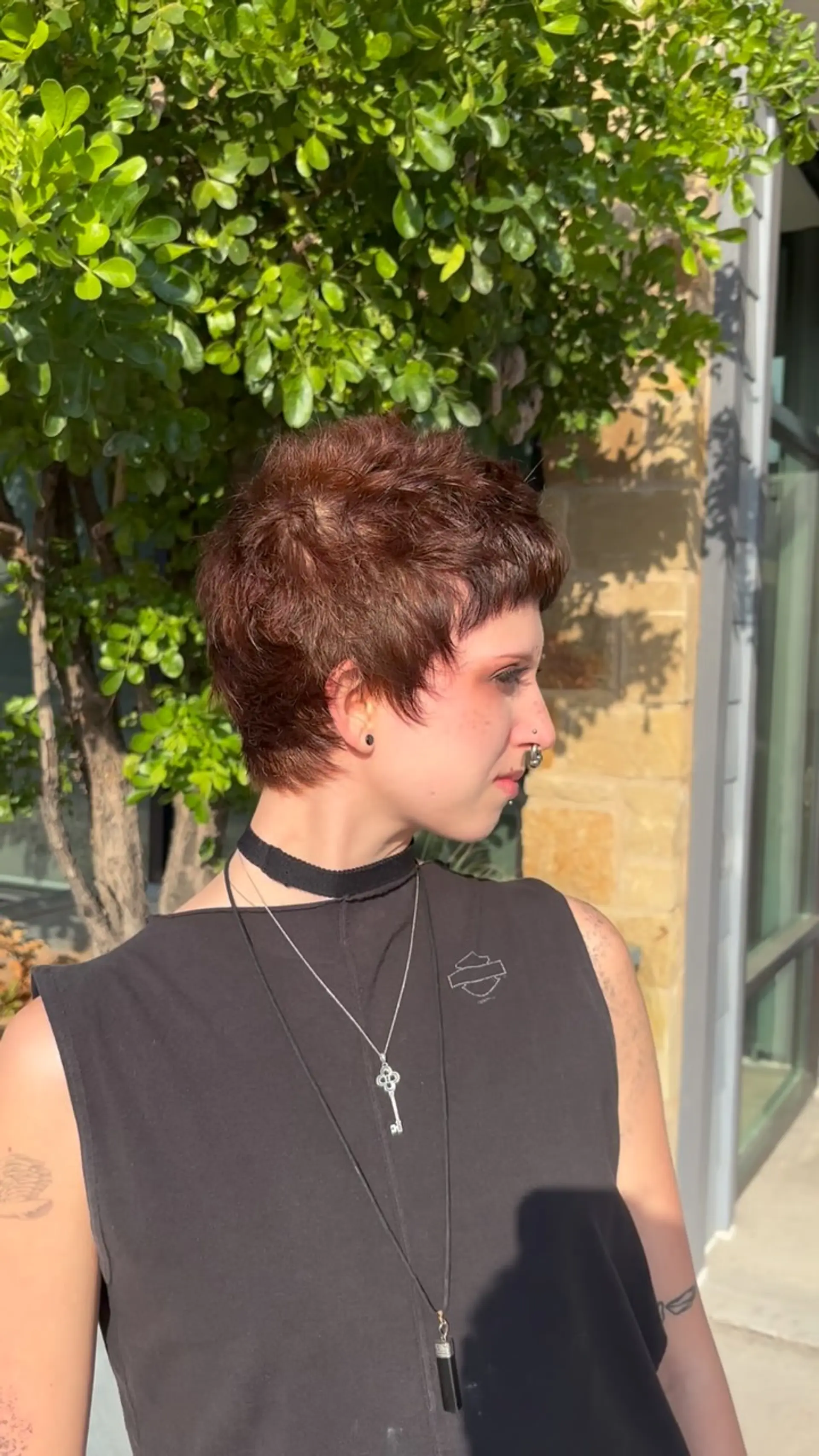 A heavily textured razor pixie cut with feathered micro bangs and pieced-out crown layers in a rich auburn tone. 1