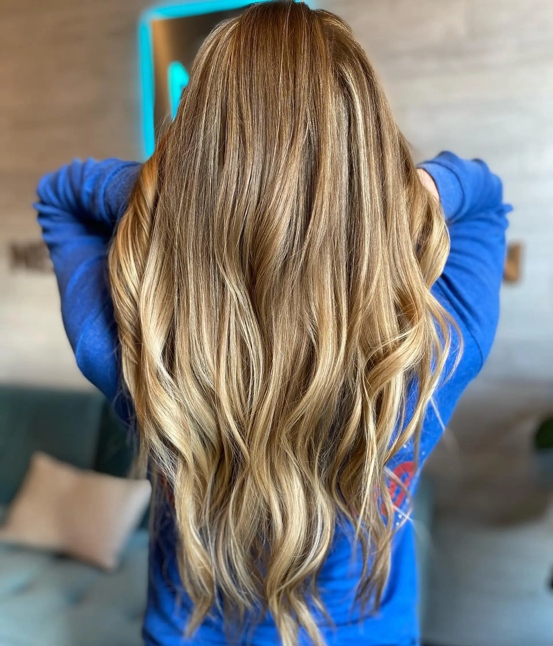 Long, healthy hair colored with seamless golden blonde balayage highlights, styled into soft, natural waves. 1