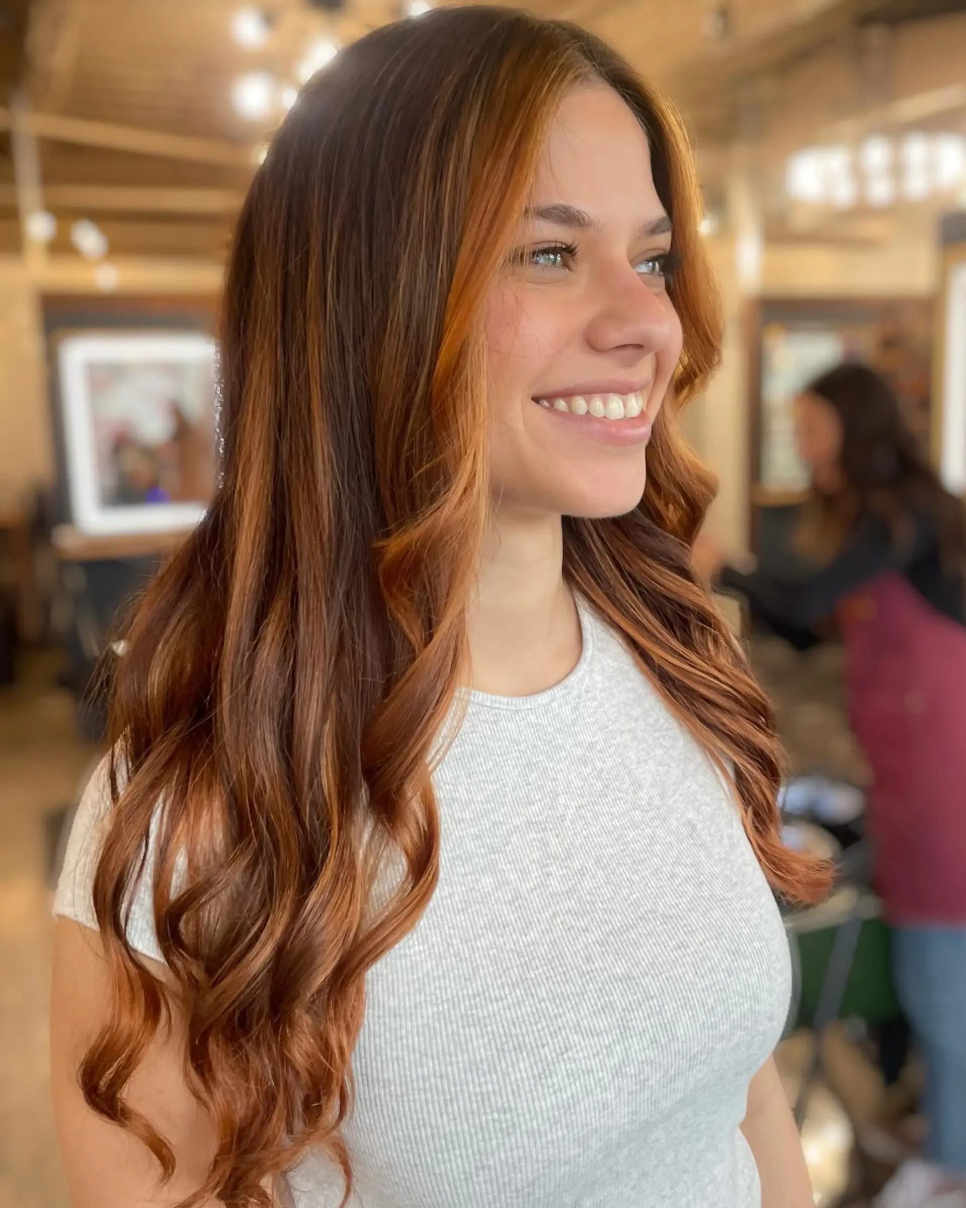 Long dimensional copper balayage styled with soft, cascading waves and bright face-framing pieces. 1