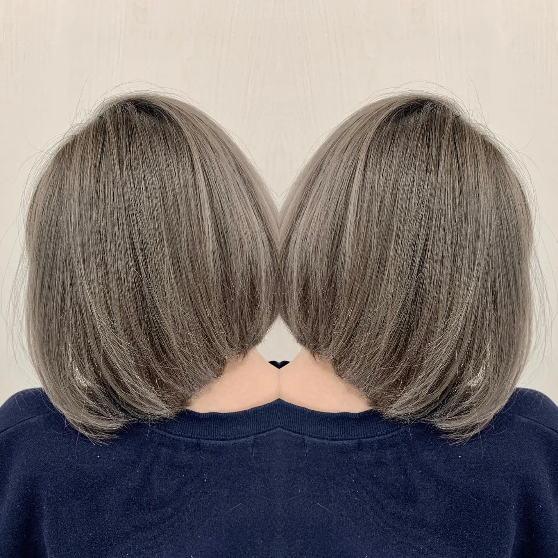 A sleek, smooth angled bob haircut finished in a cool-toned smokey beige shade. 1