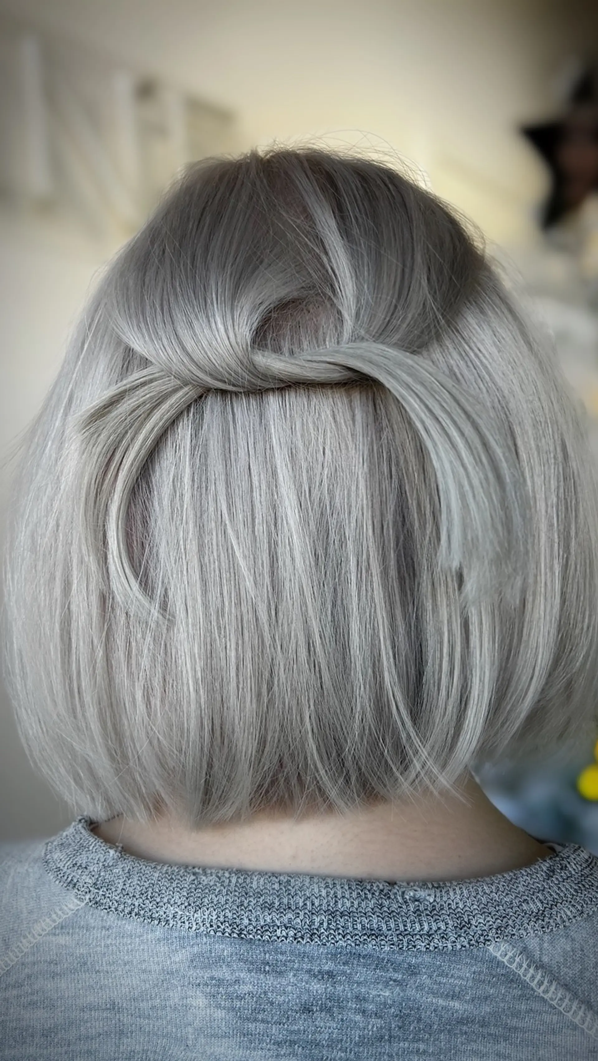 A sleek platinum blonde bob styled with a delicate half-up twist detail at the back. 1