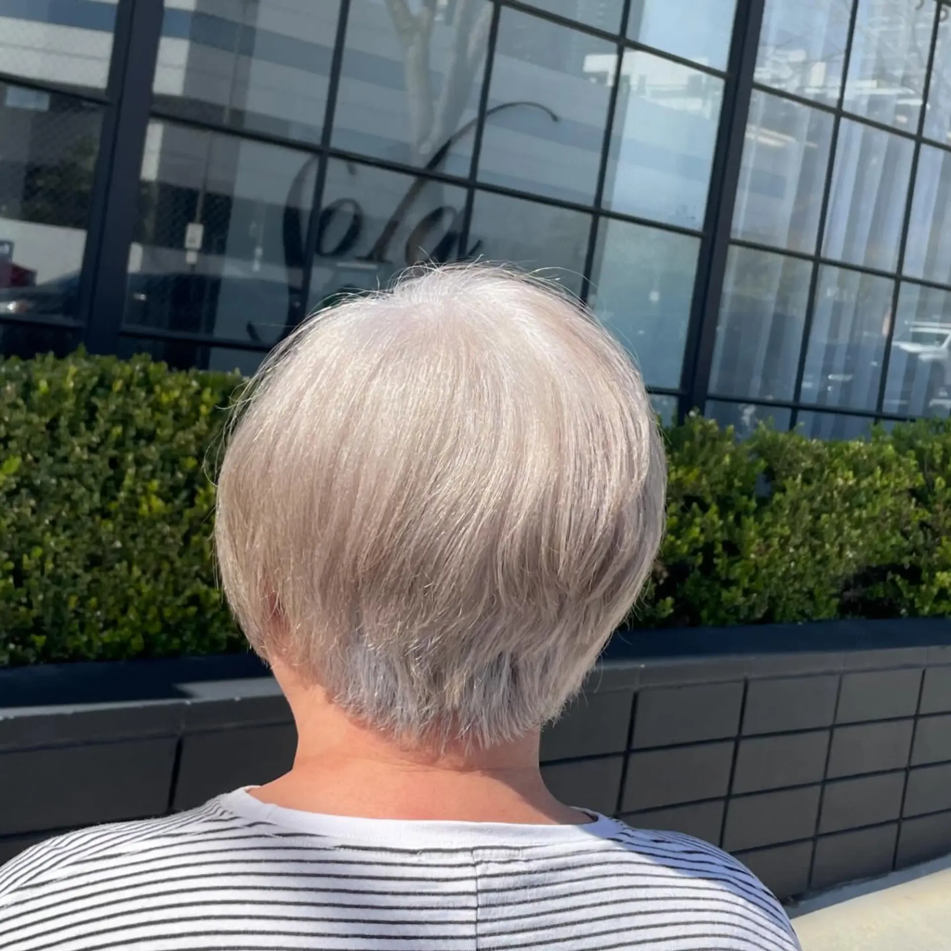 A sleek, tapered short pixie cut finished in an icy platinum silver blonde tone. 1