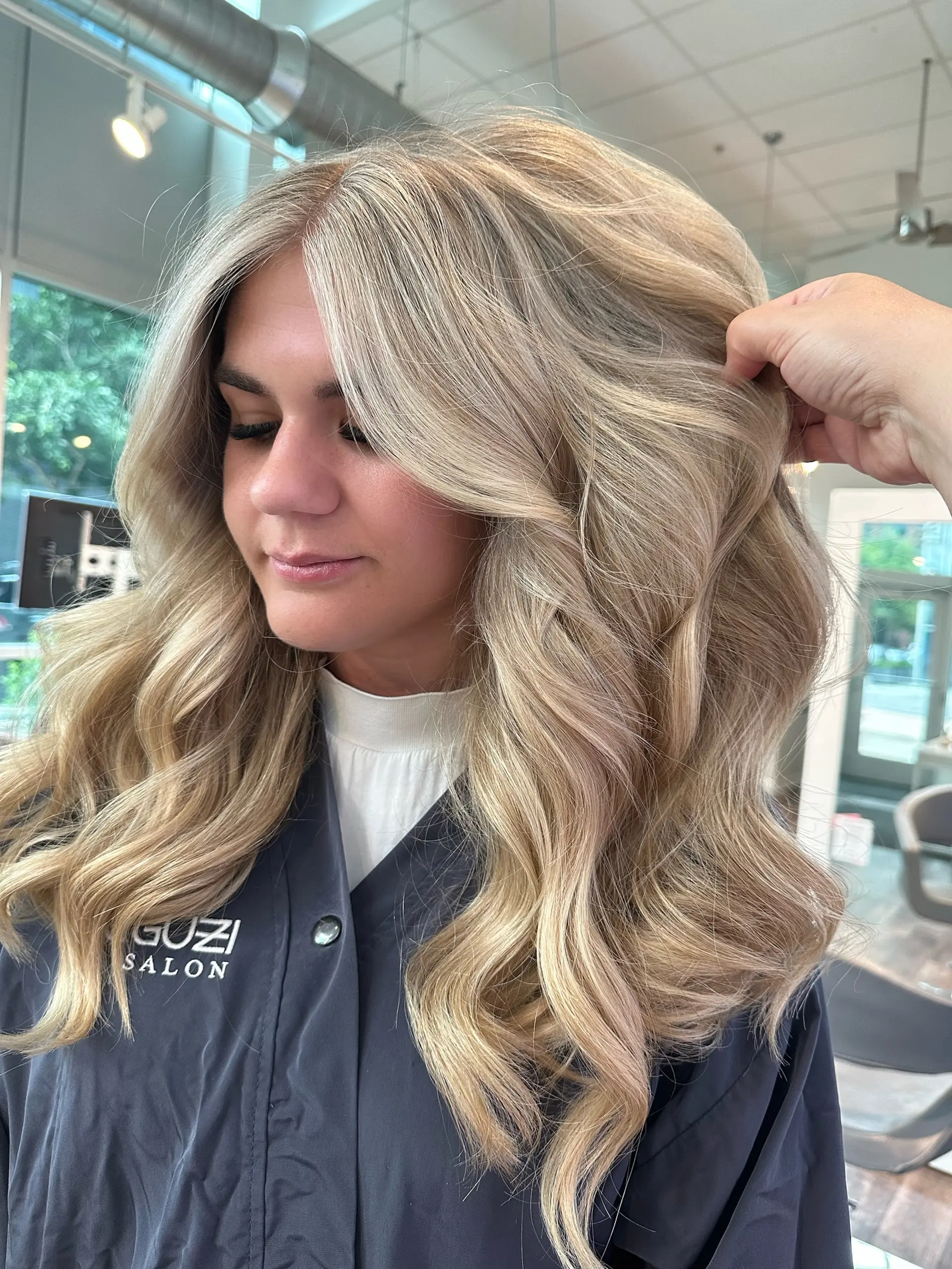 A long wavy hairstyle with a seamless balayage, creating a sun-kissed blonde look. 1