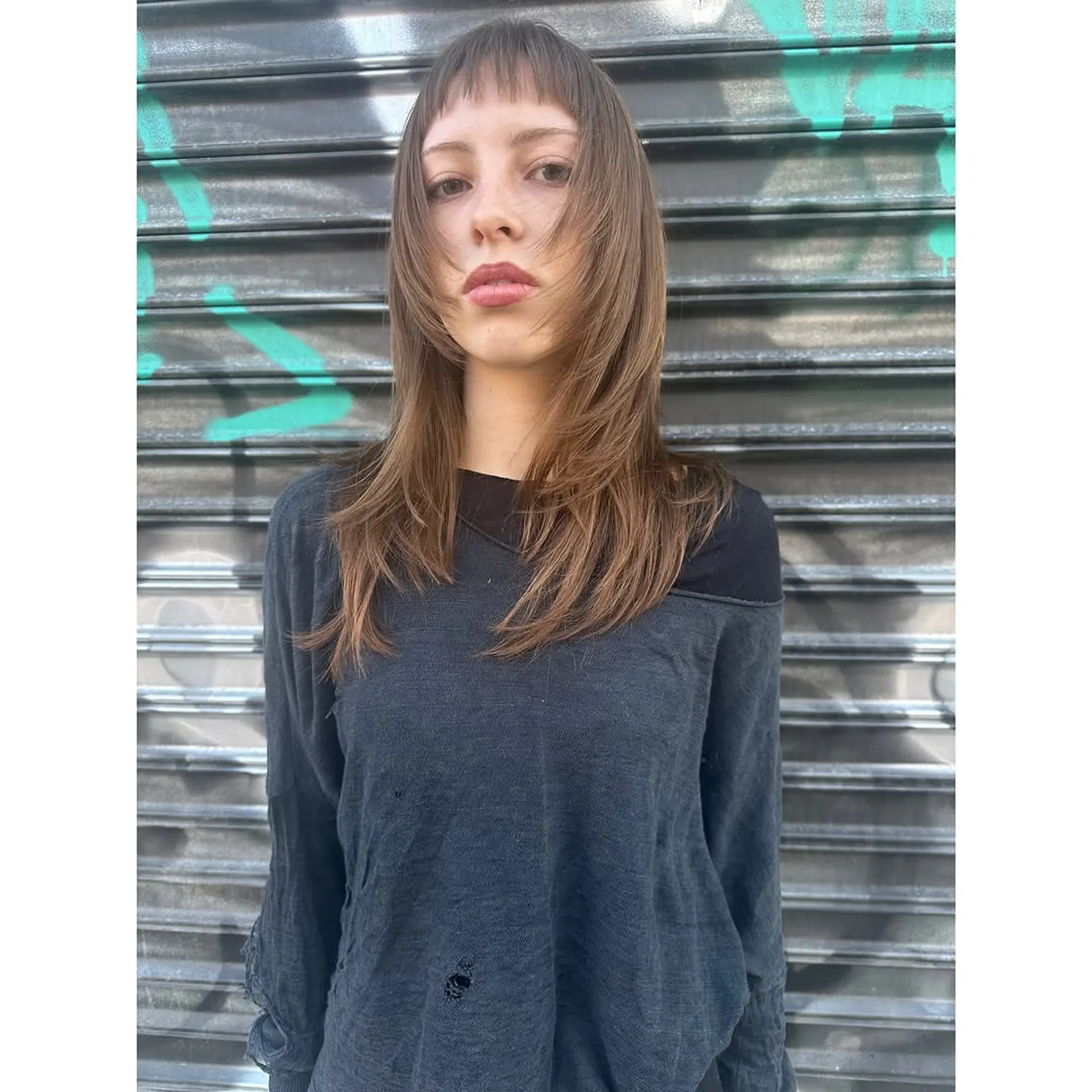 A modern shag with layered medium-length hair and short baby bangs. 1