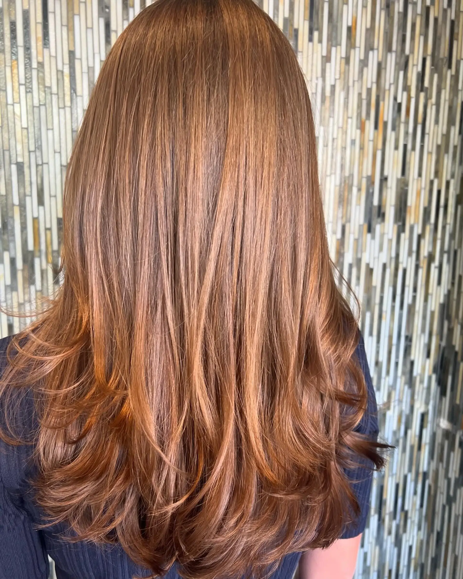 Long warm auburn hair with cascading layers and soft flipped ends. 1