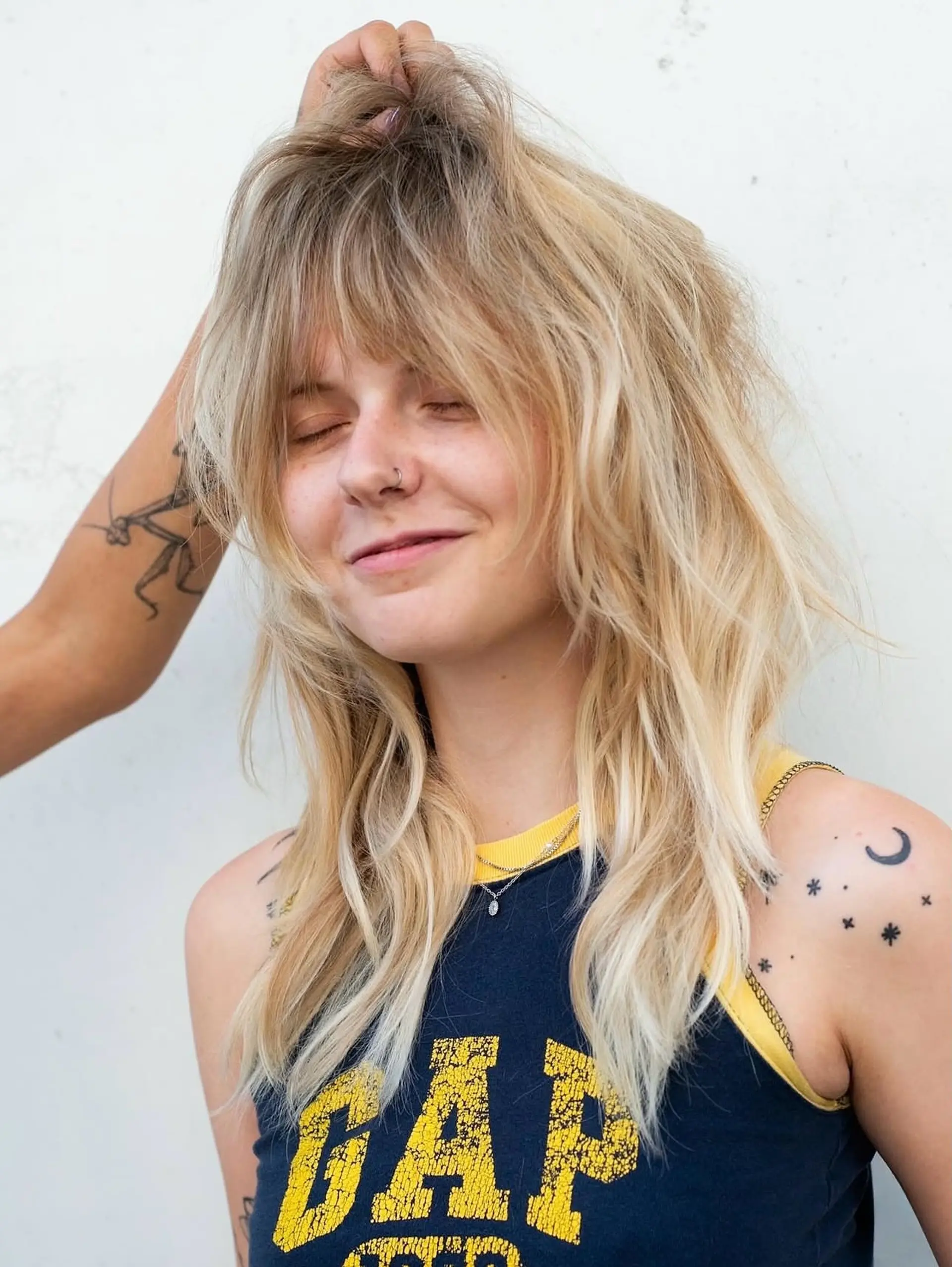 A heavily layered blonde shag haircut with choppy, textured fringe bangs and tousled face-framing layers. 1