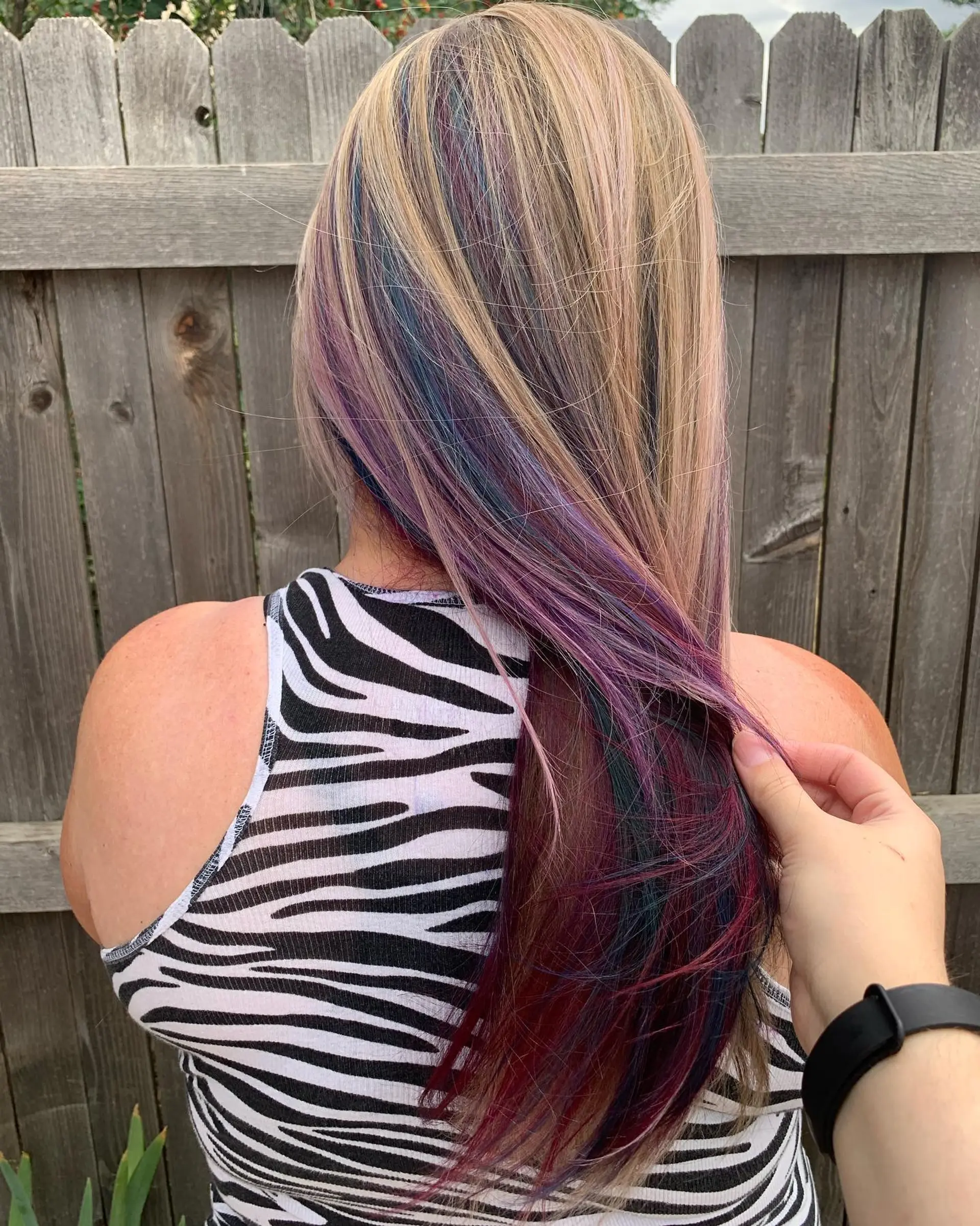 Long straight blonde hair with an underlayer of vivid peekaboo highlights in purple, blue, and magenta tones. 1
