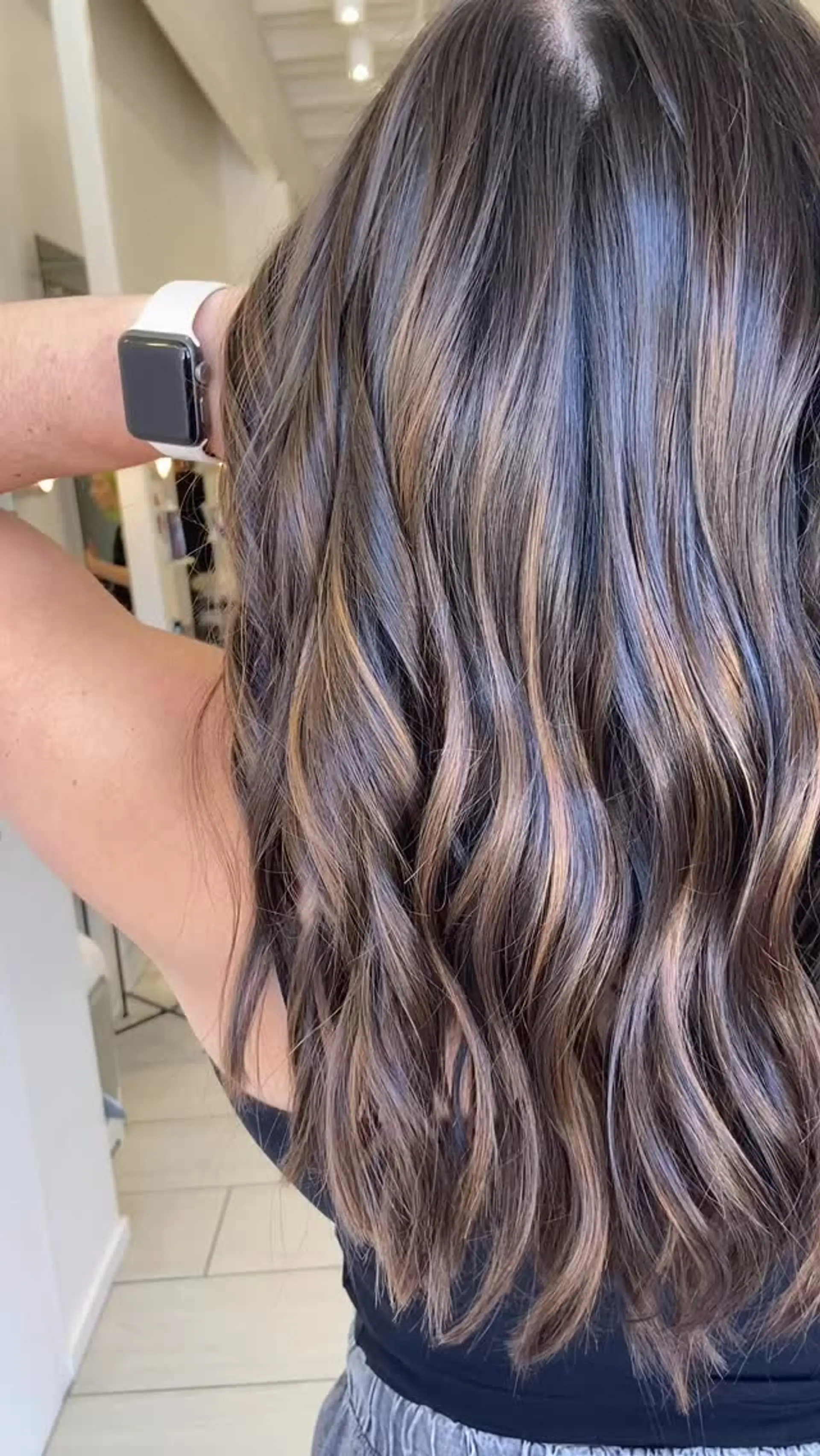 Long dimensional brunette hair with soft caramel balayage highlights styled in gentle waves. 1