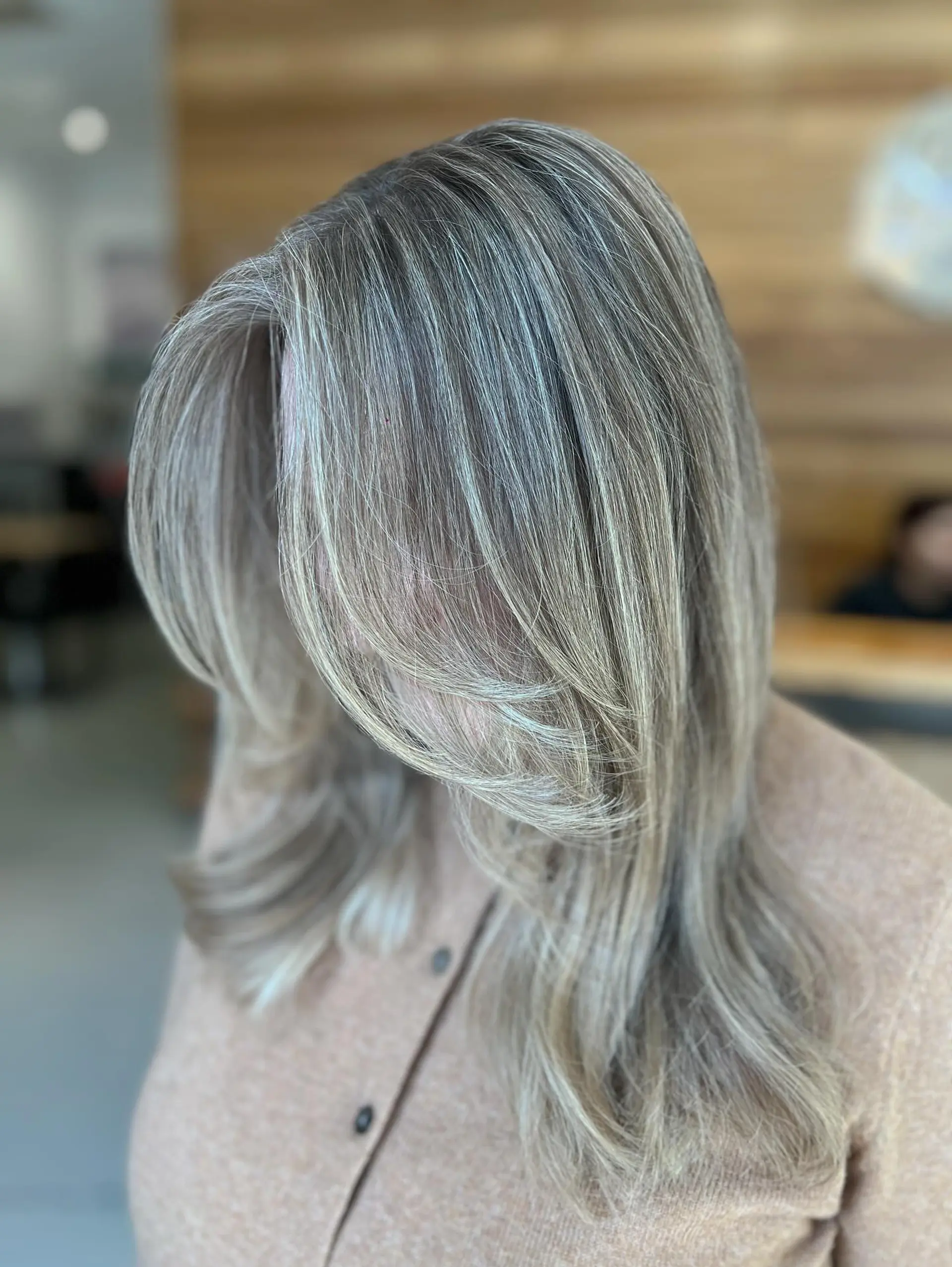 Medium-to-long layered hairstyle featuring blended cool ash blonde highlights with soft, face-framing feathered layers. 1