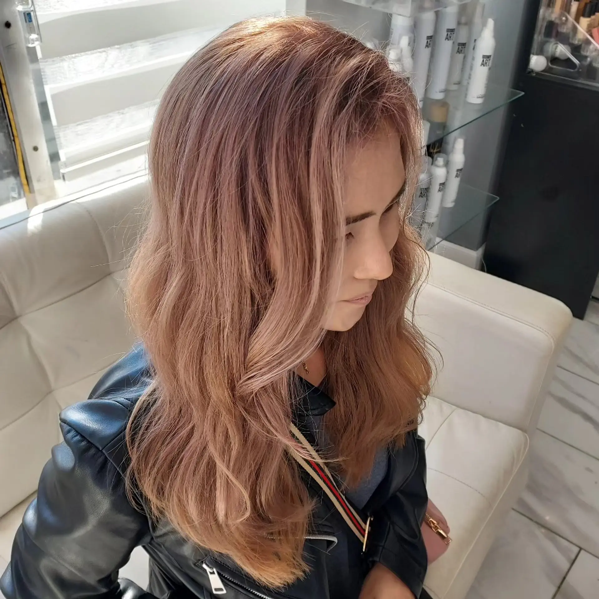 Long layered hair colored in a smoky dusty rose tone, styled into soft cascading waves. 1