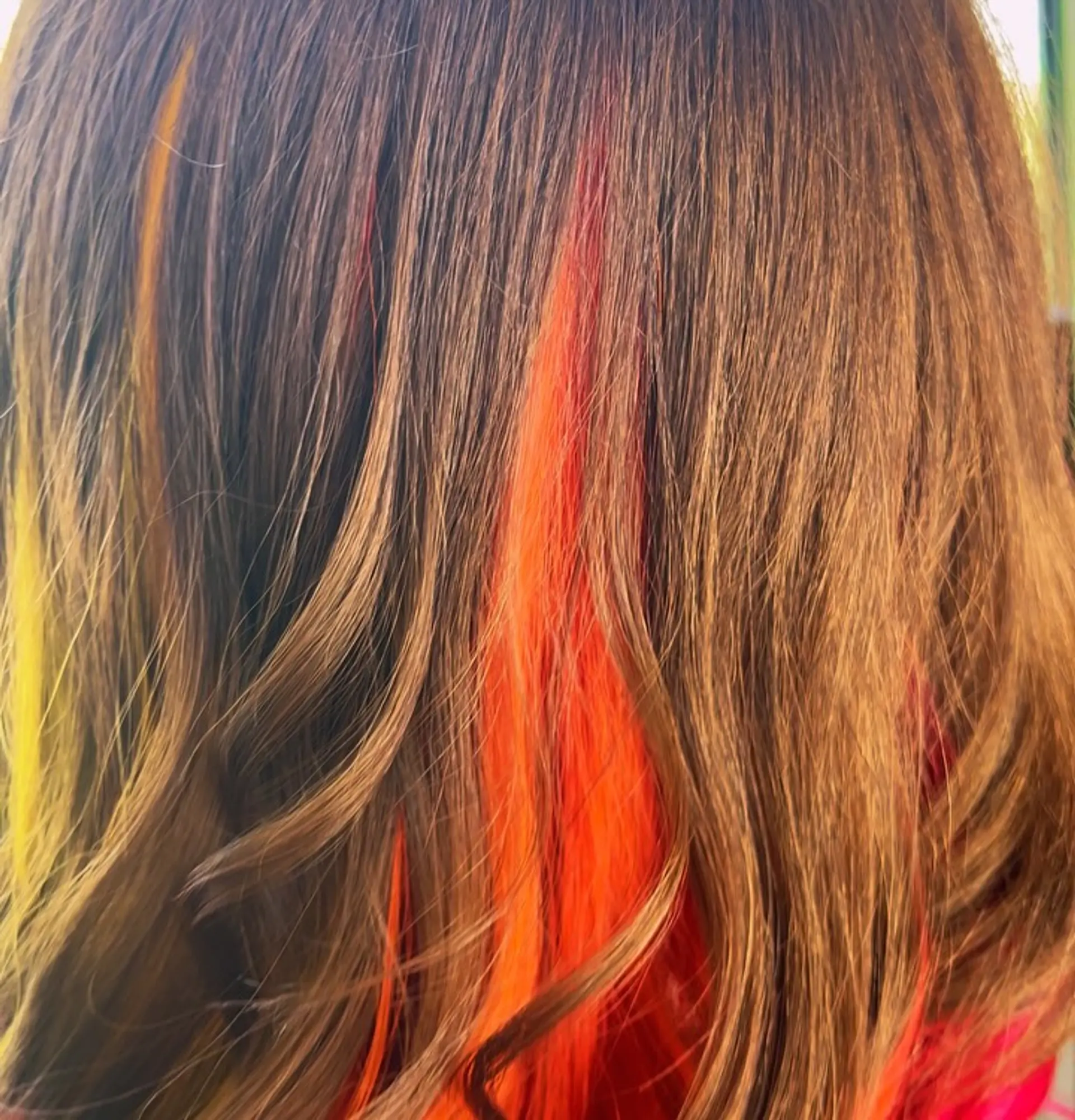 Medium brown hair styled with bright orange, red, and yellow peekaboo highlights underneath. 1