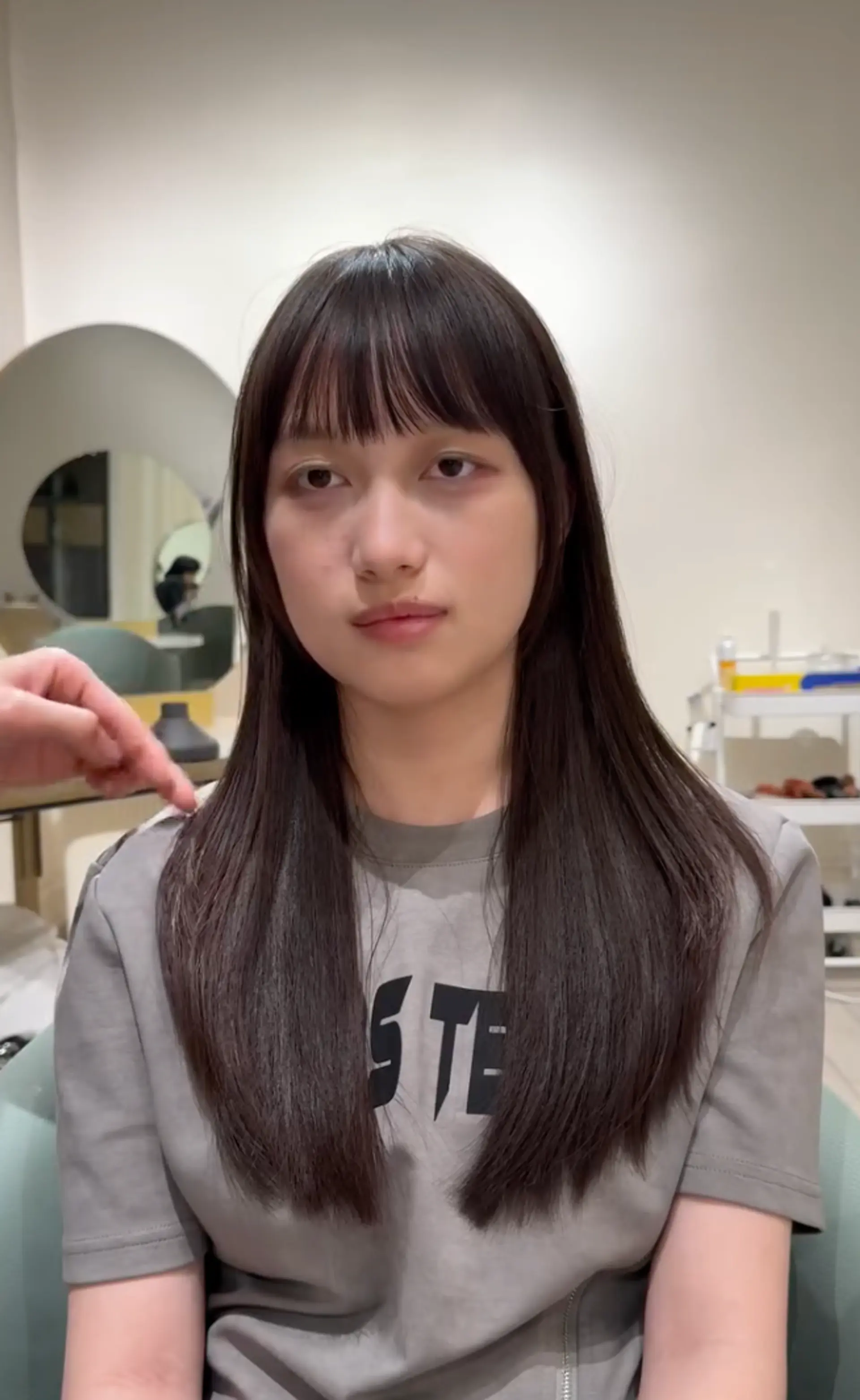 Long, straight, black hair with blunt bangs, a center part, and soft layers. 2