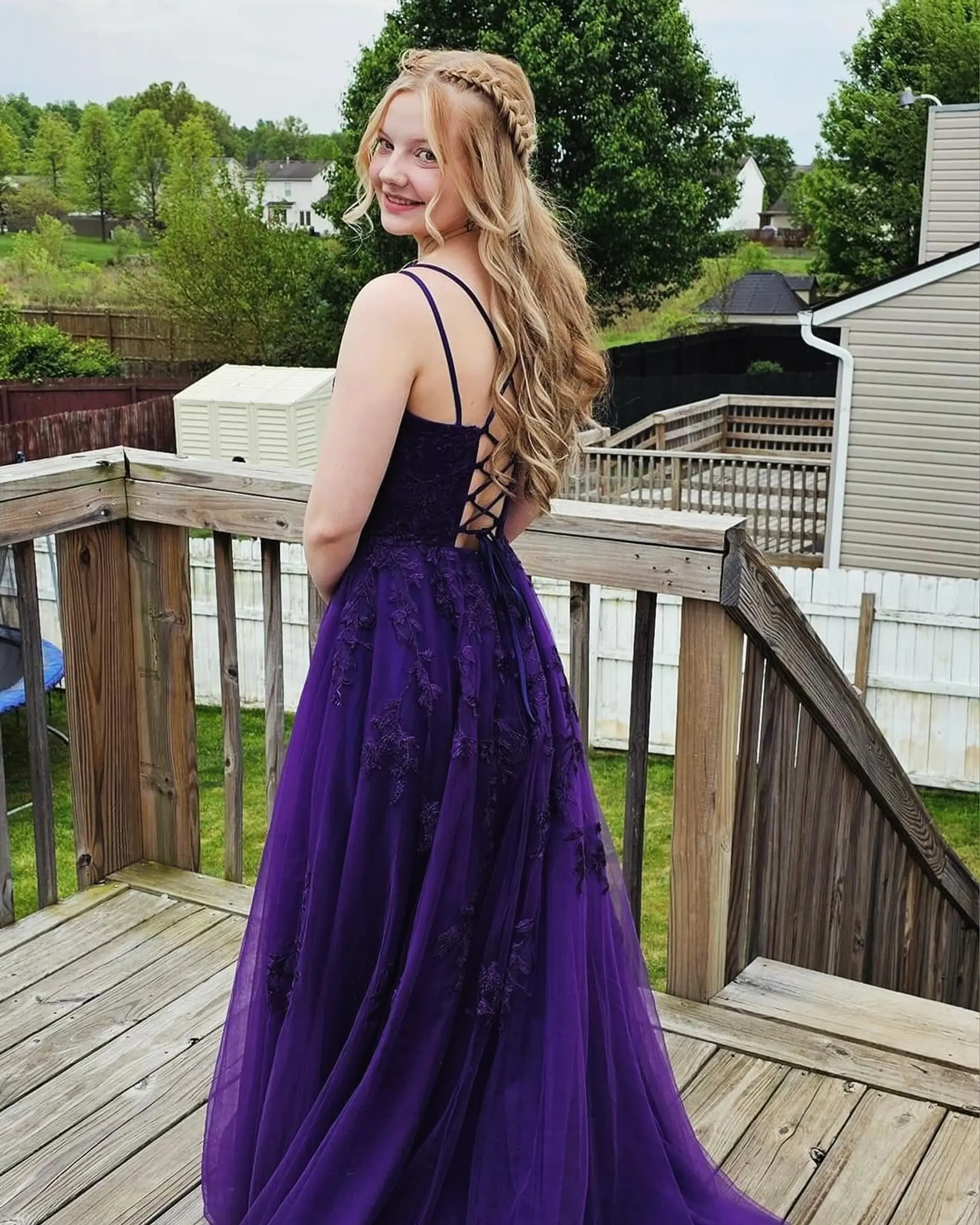 A romantic half-up half-down prom hairstyle featuring a side Dutch crown braid and soft, cascading curls. 1