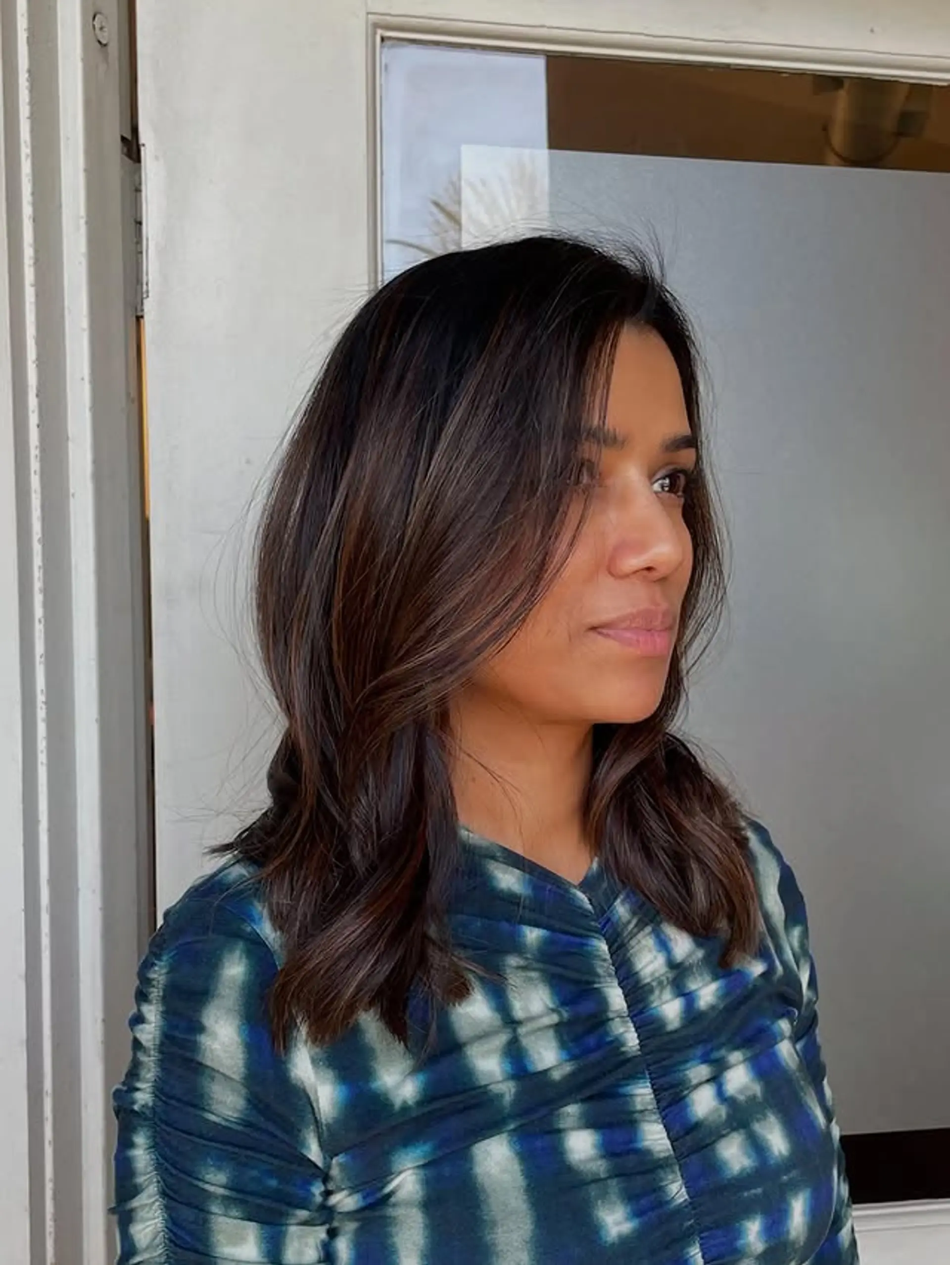A shoulder-length wavy hairstyle with a brunette balayage and face-framing layers. 1