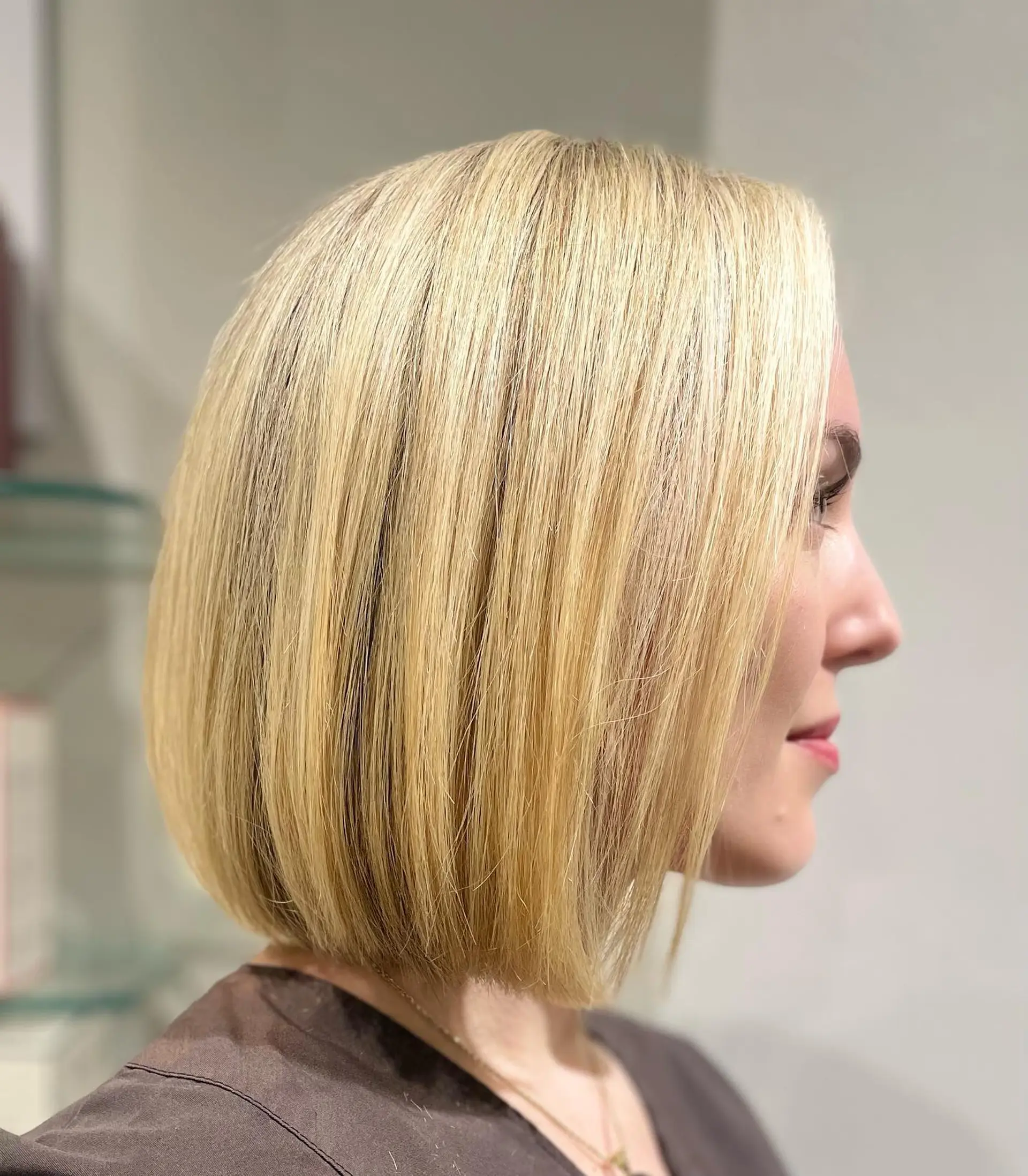 A sleek, chin-length classic bob cut straight with dimensional golden blonde highlights. 1