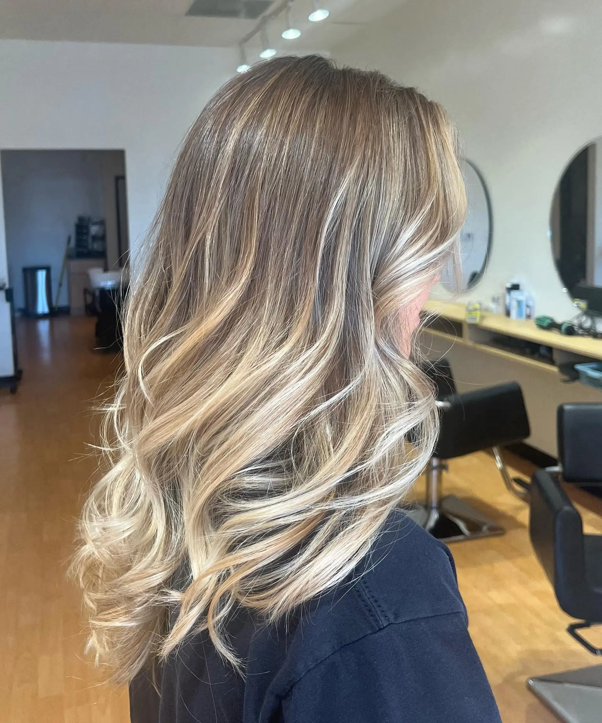 Long multi-tonal blonde balayage styled in soft, cascading waves. 1