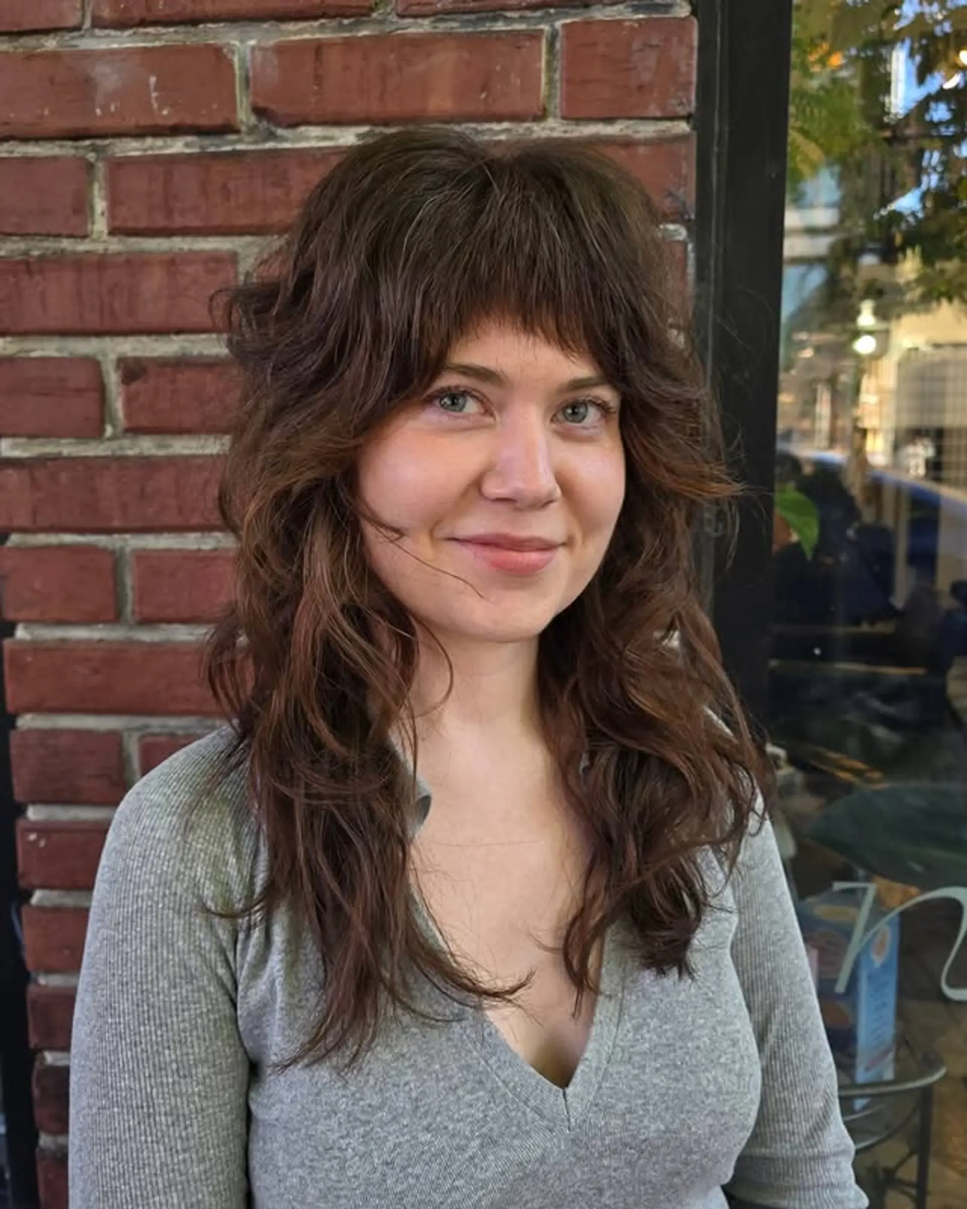 A trendy, layered shag haircut with face-framing curtain bangs, perfect for wavy hair. 1