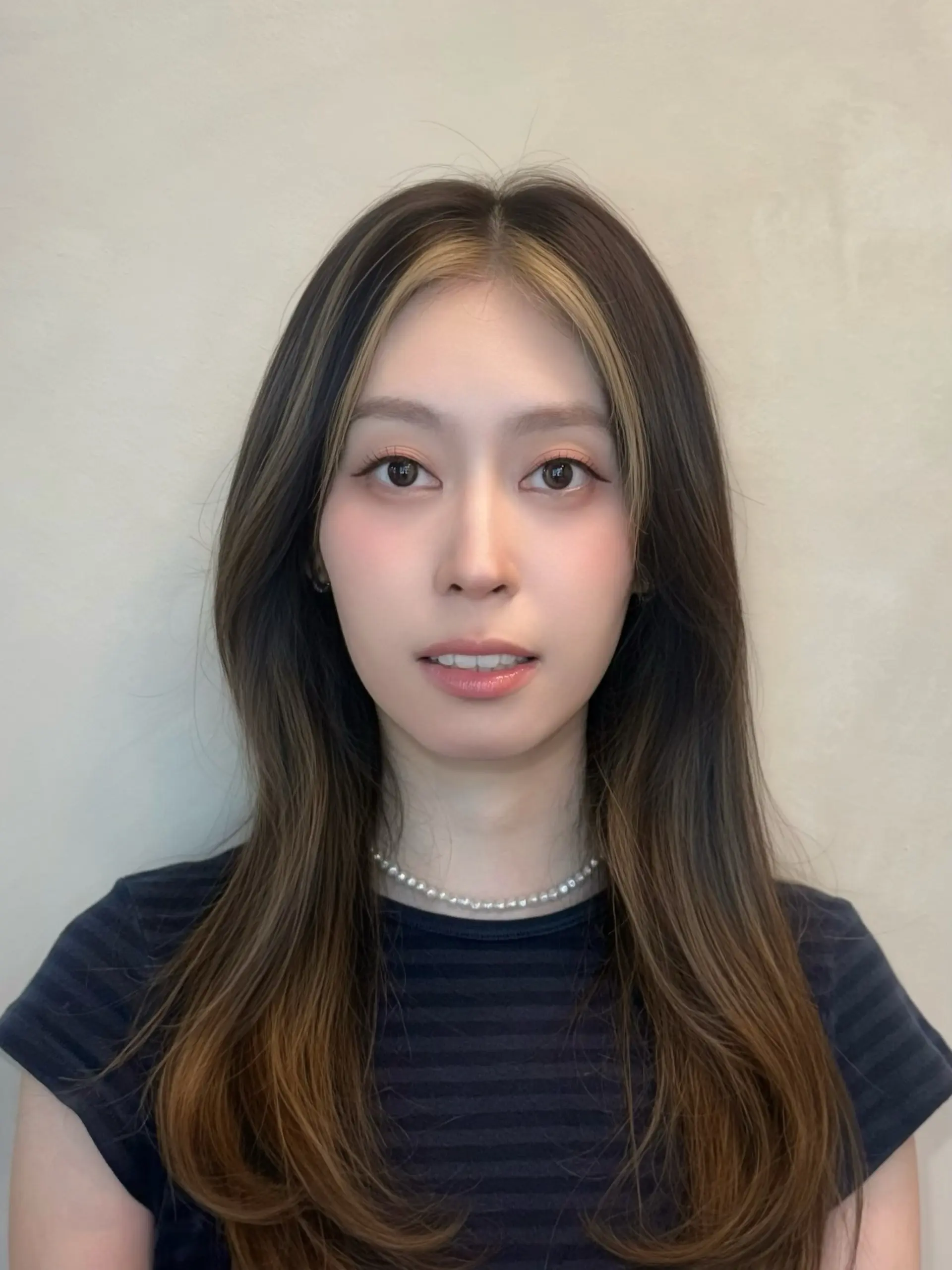 Long smooth dark brown hair styled with prominent blonde face-framing money piece highlights. 1