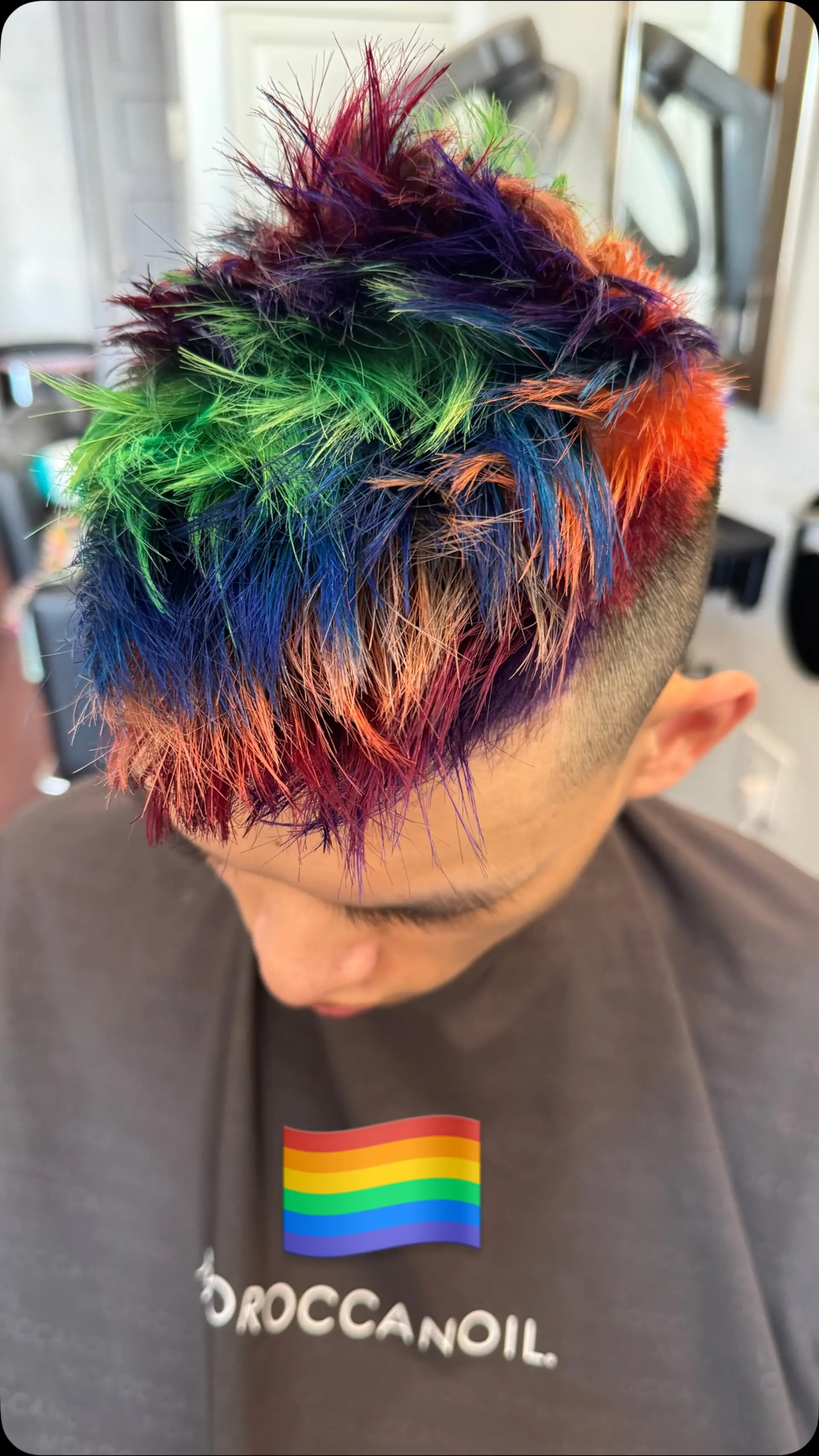A textured short haircut with clipper-faded sides and a spiky top colored in vibrant rainbow tones. 1