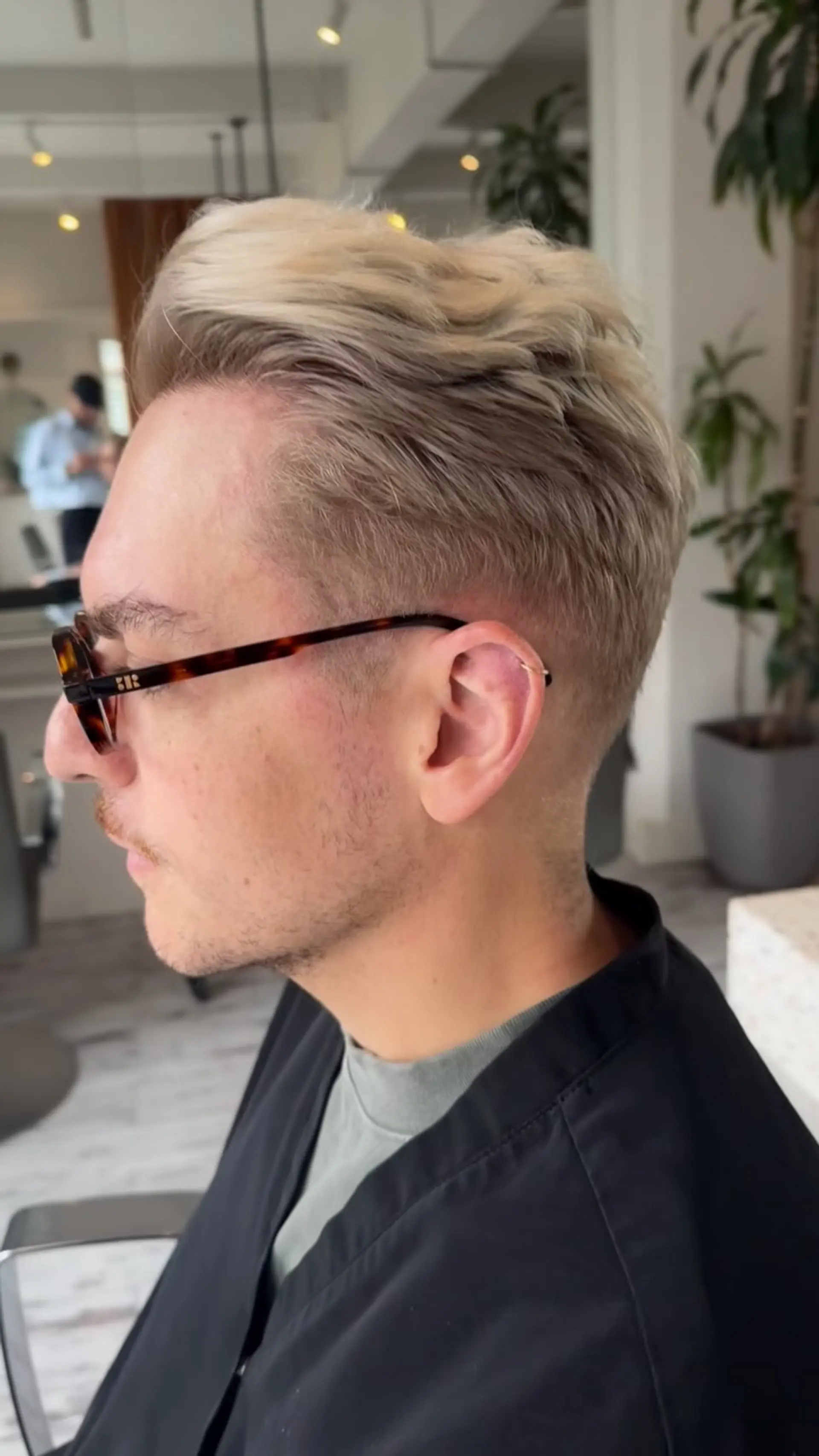 A cool-toned ash blonde textured crop with a neat taper around the ears and neck, styled with soft volume on top. 1