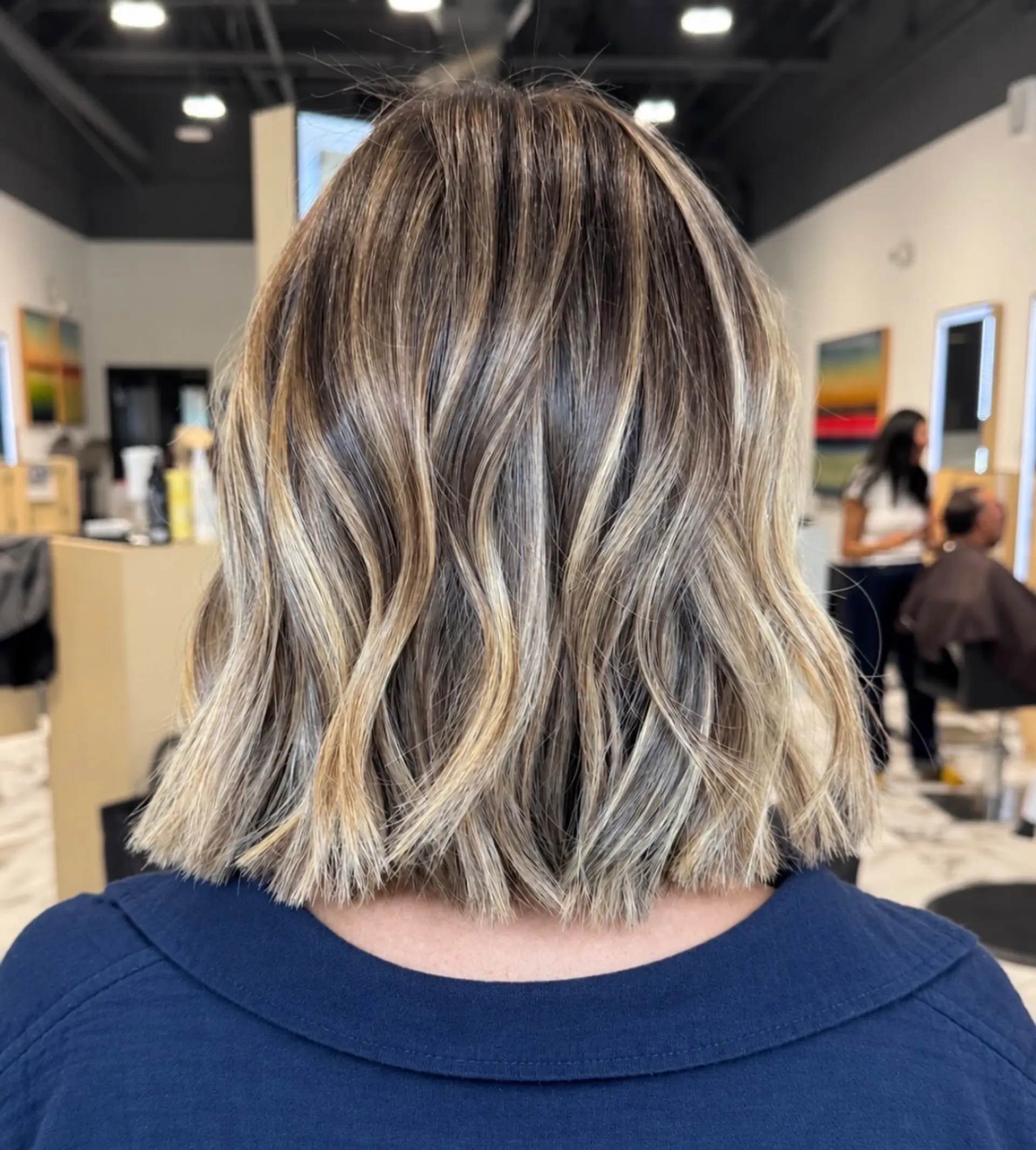 A blunt, textured shoulder-length bob styled with subtle bends and dimensional blonde highlights over a soft brown shadow root. 1