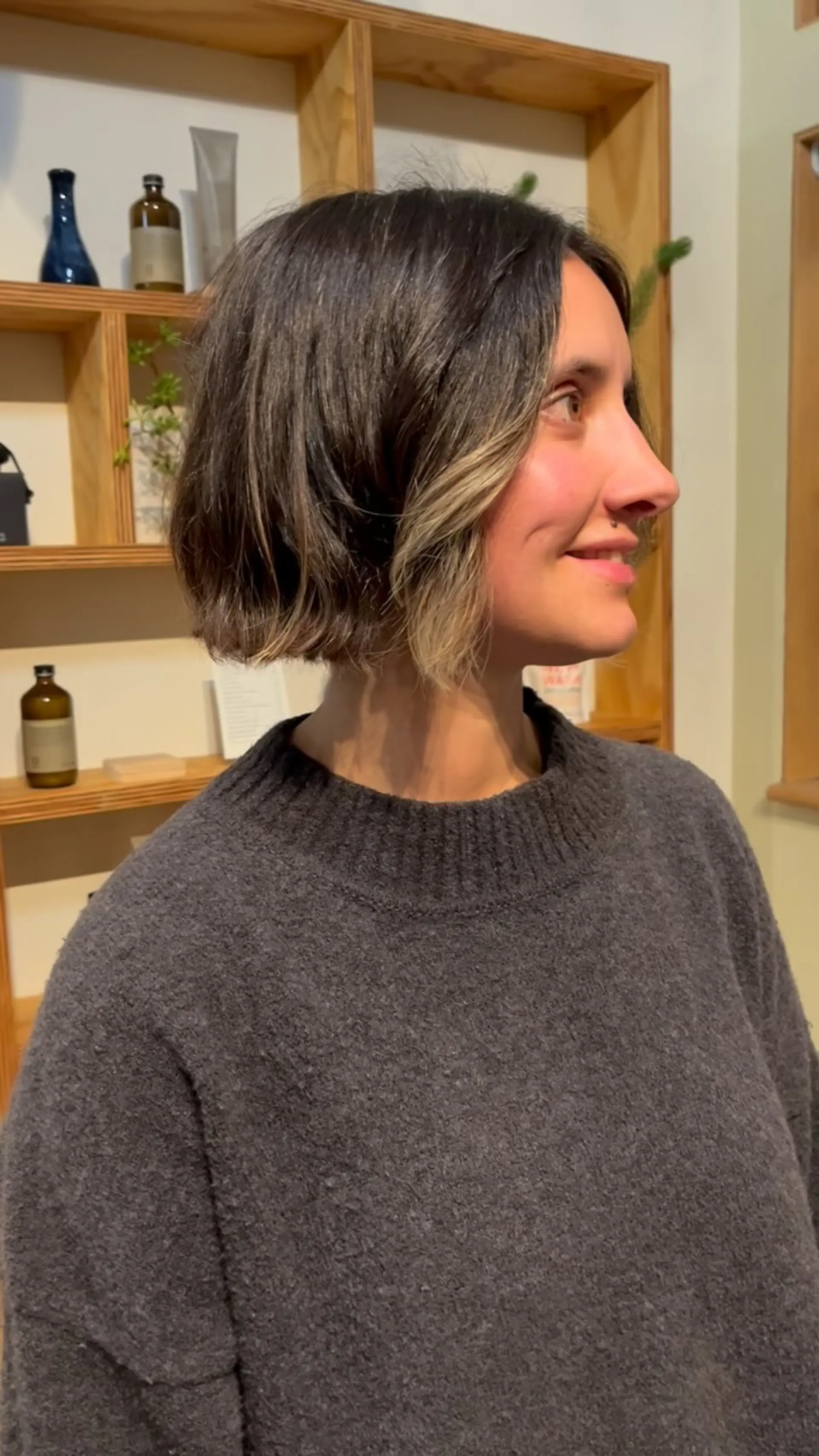 A modern boxy short bob featuring dark brown hair with bright blonde face-framing highlights and natural wave texture. 1