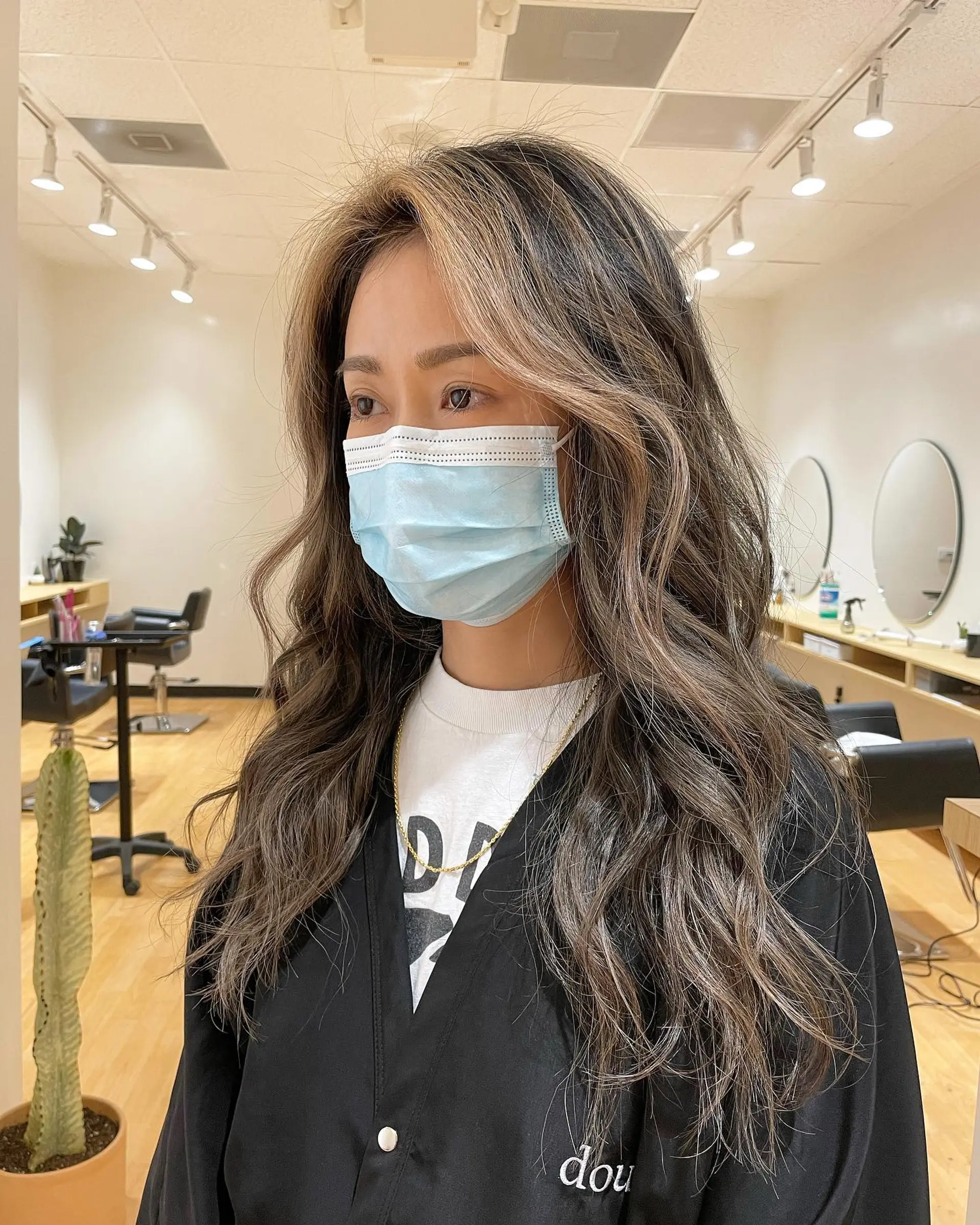 Long wavy brunette hair styled with dimensional cool-toned blonde highlights, lowlights, and soft face-framing pieces. 1