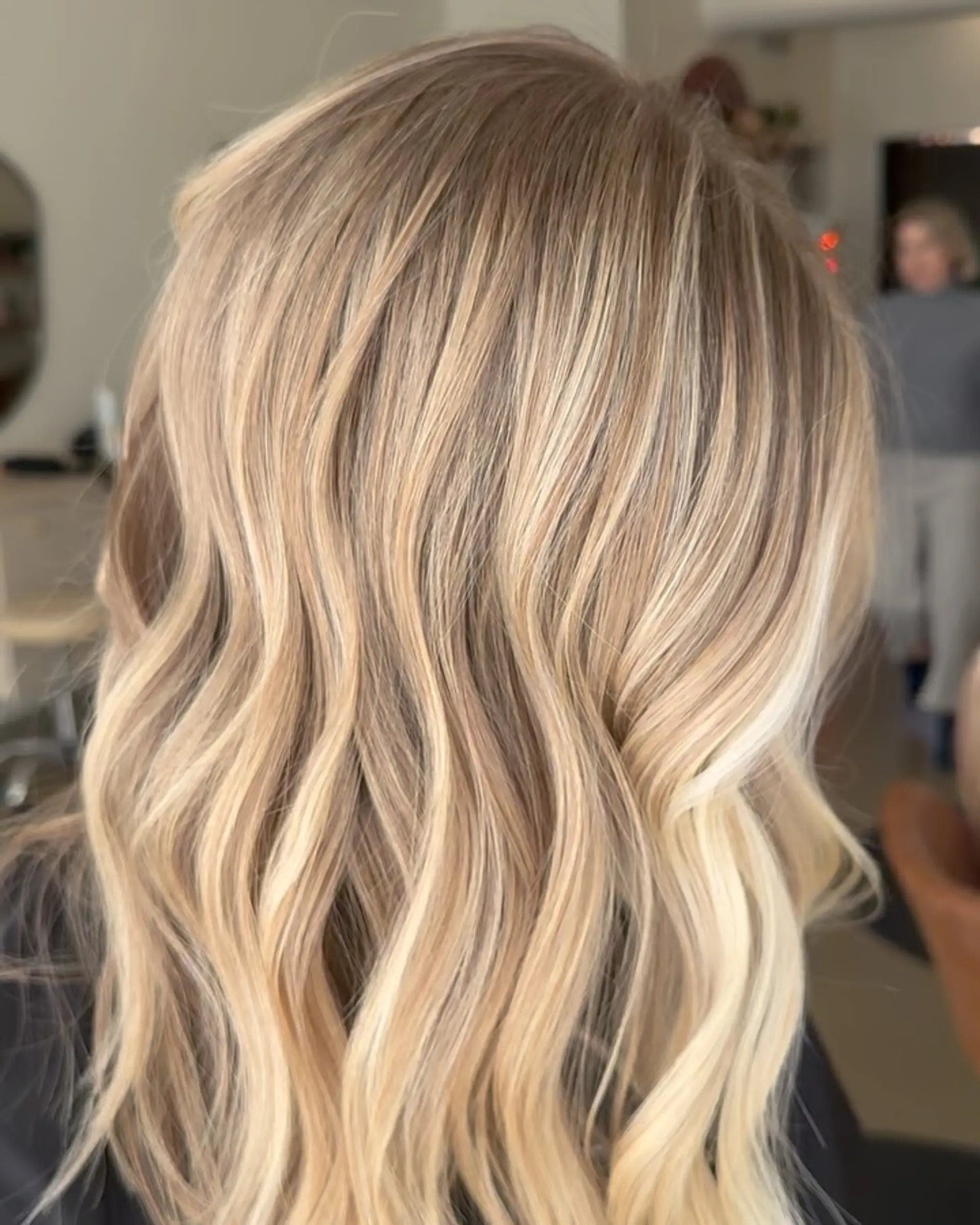 Medium-to-long seamless blonde balayage with soft, dimensional waves. 1