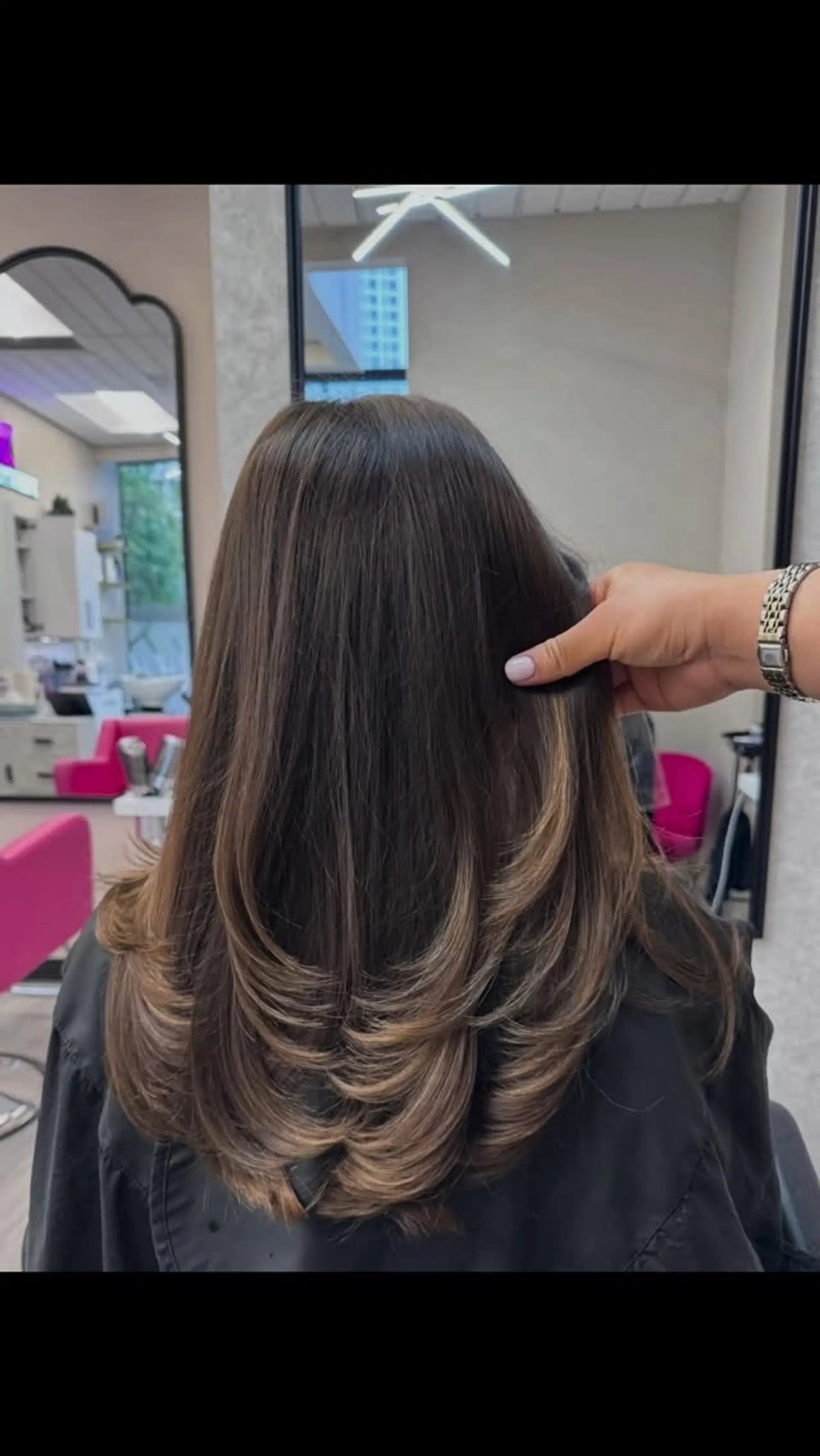 Long dark brown hair cut into cascading curved layers with a rounded, bouncy blowout finish. 1