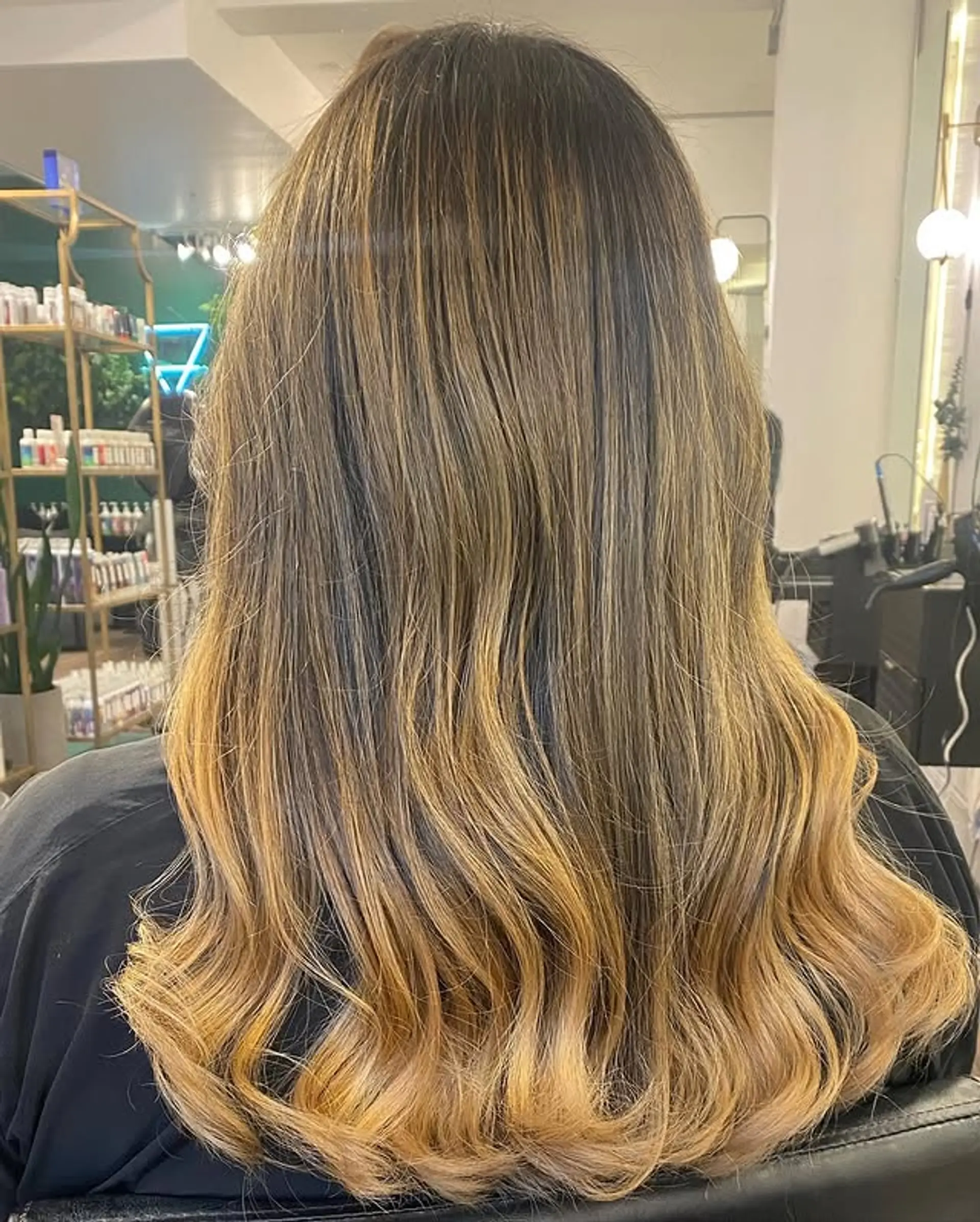 Long, wavy hair with a golden blonde balayage that transitions from brown roots. 1