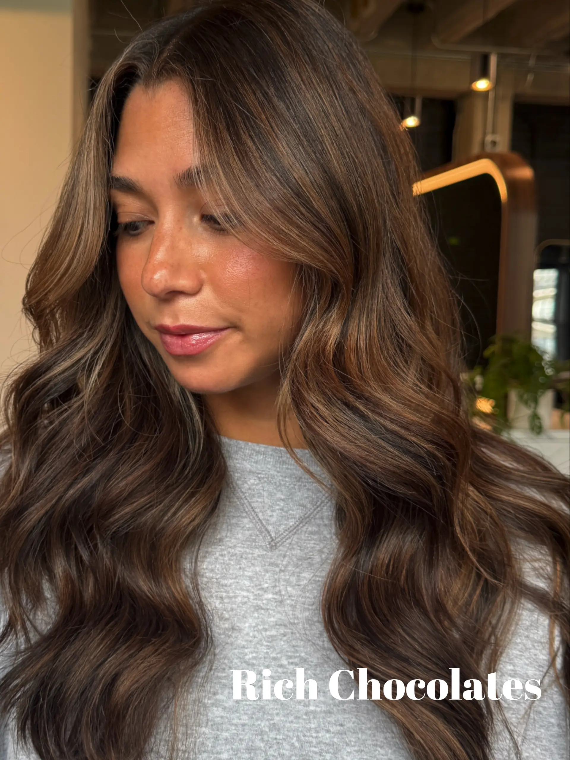 Long chocolate brown hair featuring subtle caramel balayage highlights styled into polished, cascading waves. 1